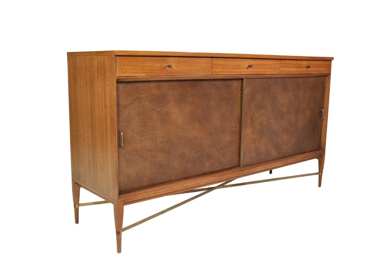 All original Paul McCobb mahogany cabinet or sideboard from The Calvin Group (earlier Irwin Collection) by Calvin Furniture, which is part of the work the designer created for Directional (model 1066). The mid-century modern credenza features: three