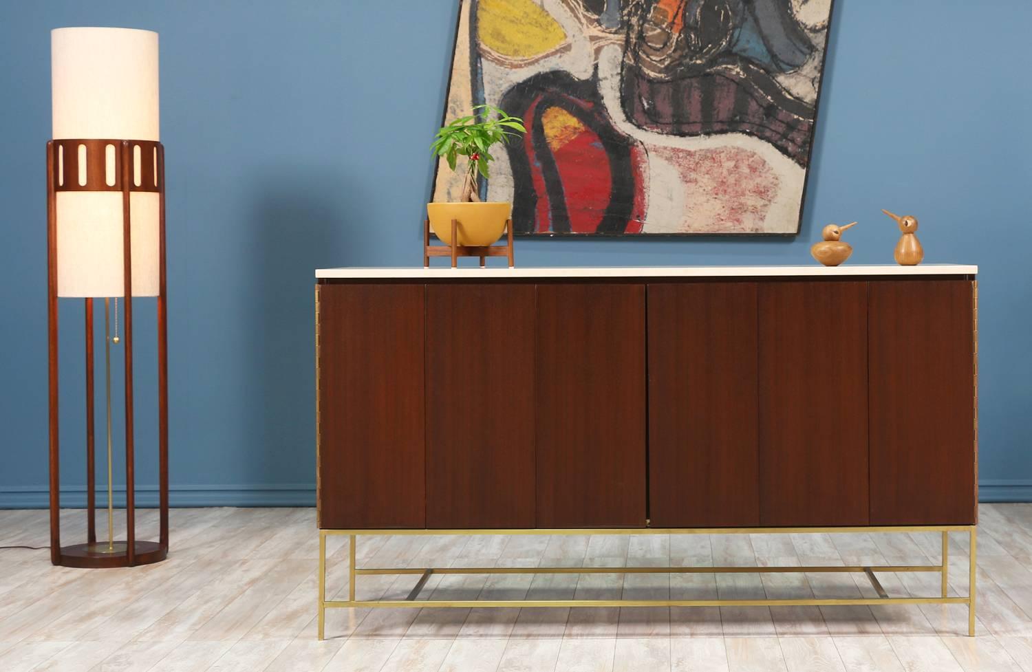 Mid Century modern credenza designed by Paul McCobb for the “Irwin Collection” at Calvin Group in the United States circa 1950’s. This stunning credenza sits on a beautiful polished brass base and features a new travertine top over the mahogany