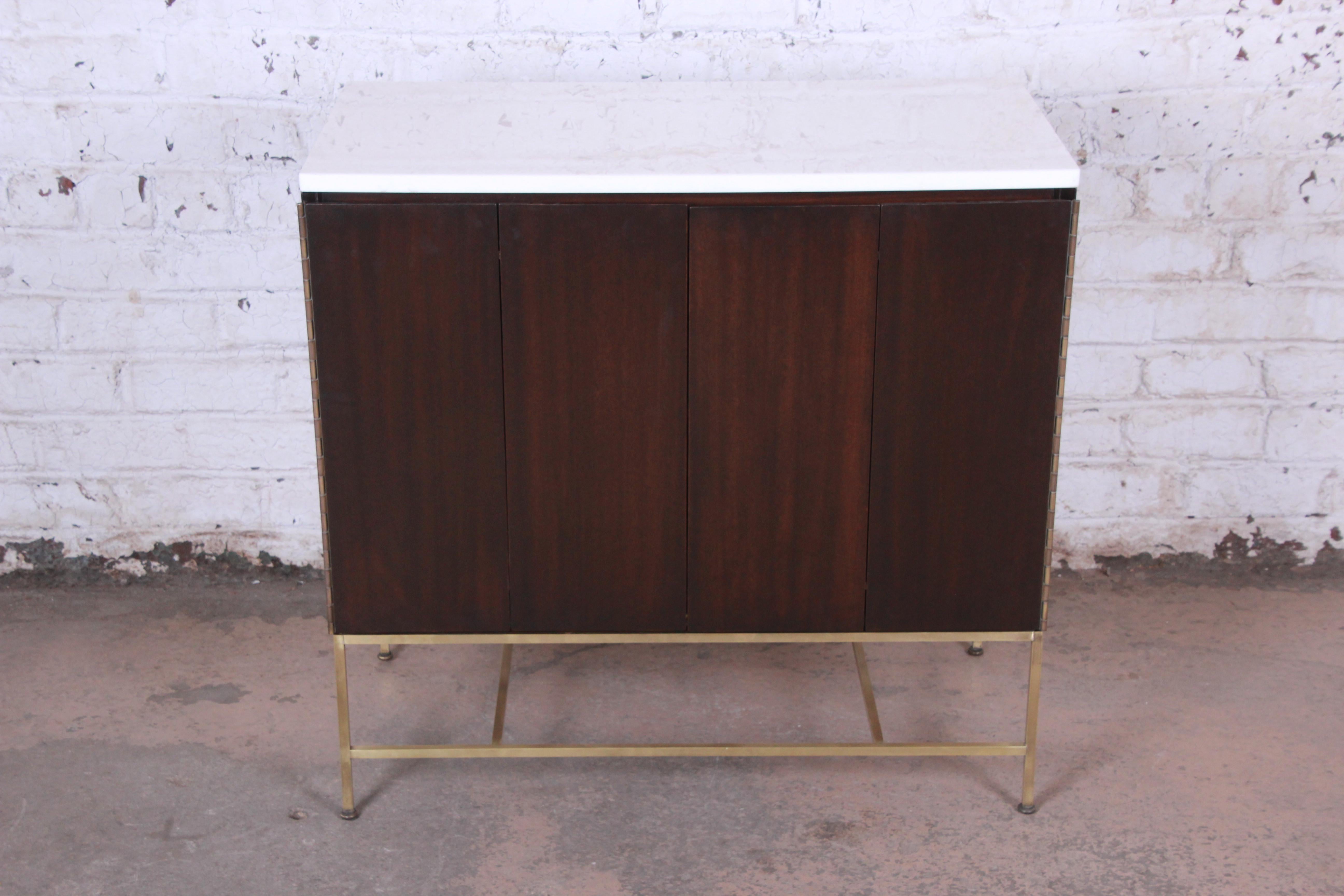 Offering an exceptional Mid-Century Modern sideboard credenza or cabinet designed by Paul McCobb for his Irwin Collection for Calvin Furniture. The credenza features gorgeous mahogany wood grain, with an original brass base and white vitrolite top.
