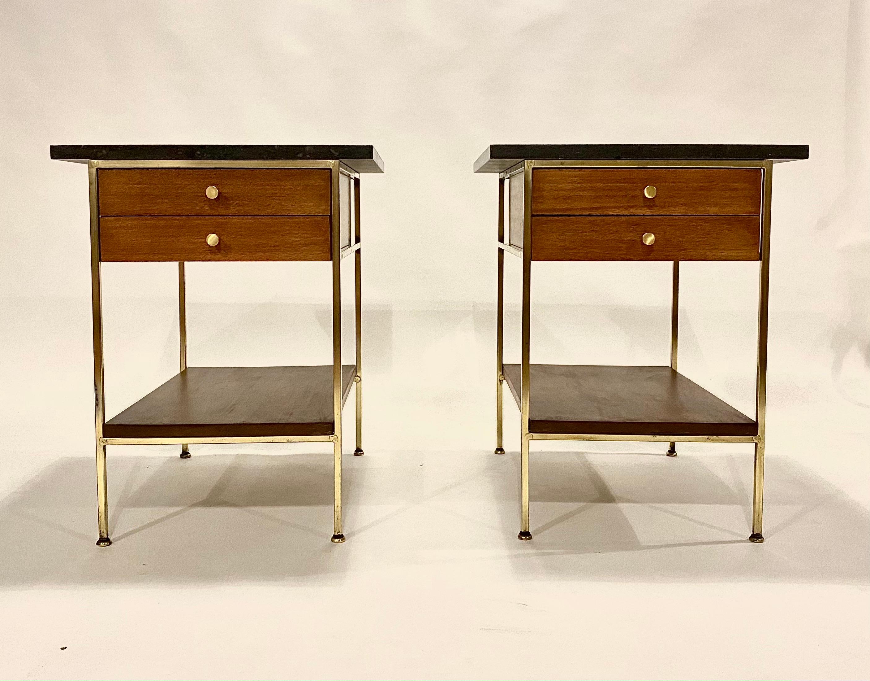 Pair of nightstands or end tables from the Irwin Collection designed by Paul McCobb for Calvin, Grand Rapids, 1950s. This set is all newly restored in hand polished brass and refinished walnut wood, original gray stone tops and replaced brass pulls.