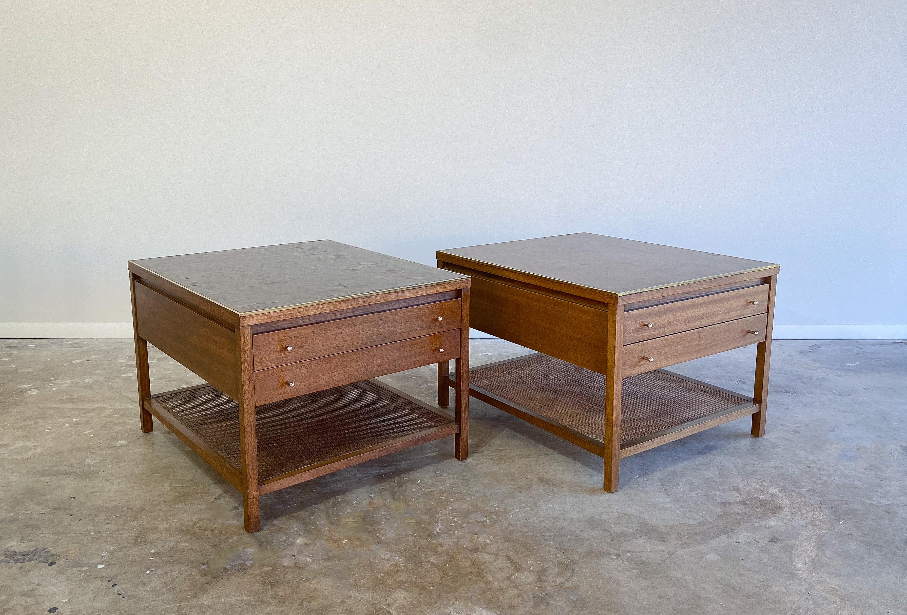 An elegant pair of mahogany and leather top side or end tables designed by Paul McCobb for the Irwin Collection, and manufactured by Calvin. 

Each features two drawers for storage. The leather tops provide a unique look to liven up your decor.