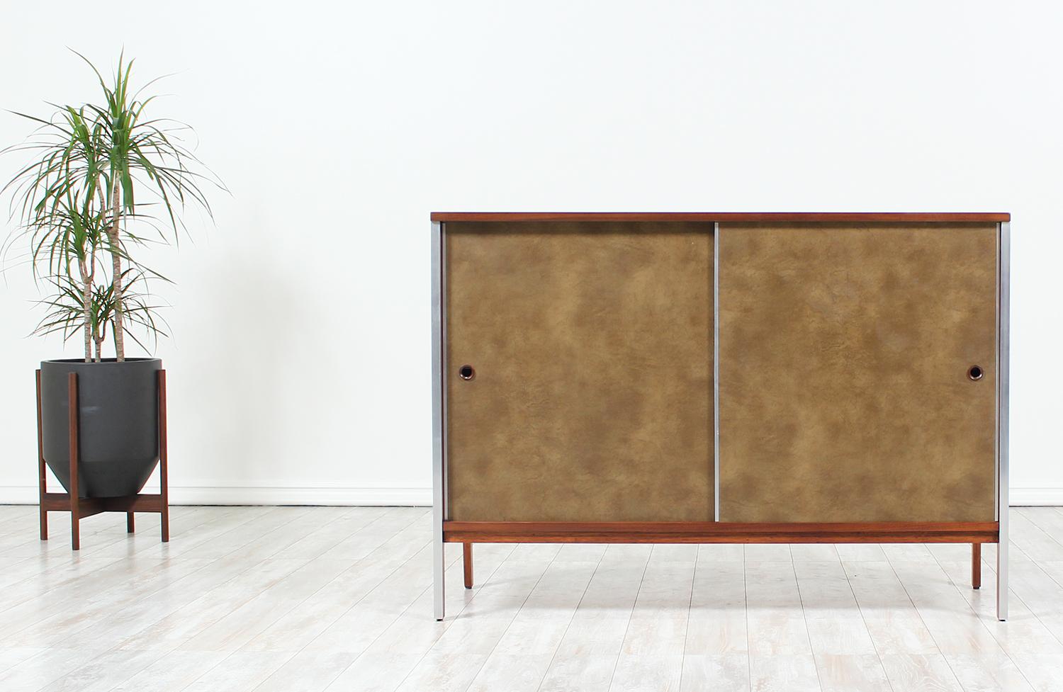 Stunning compact credenza designed by Paul McCobb for Calvin Furnitures’ “Linear Group” line in the United States circa 1950’s. This exceptional credenza features a walnut wood body with aluminum details that run up the legs and front sides. The