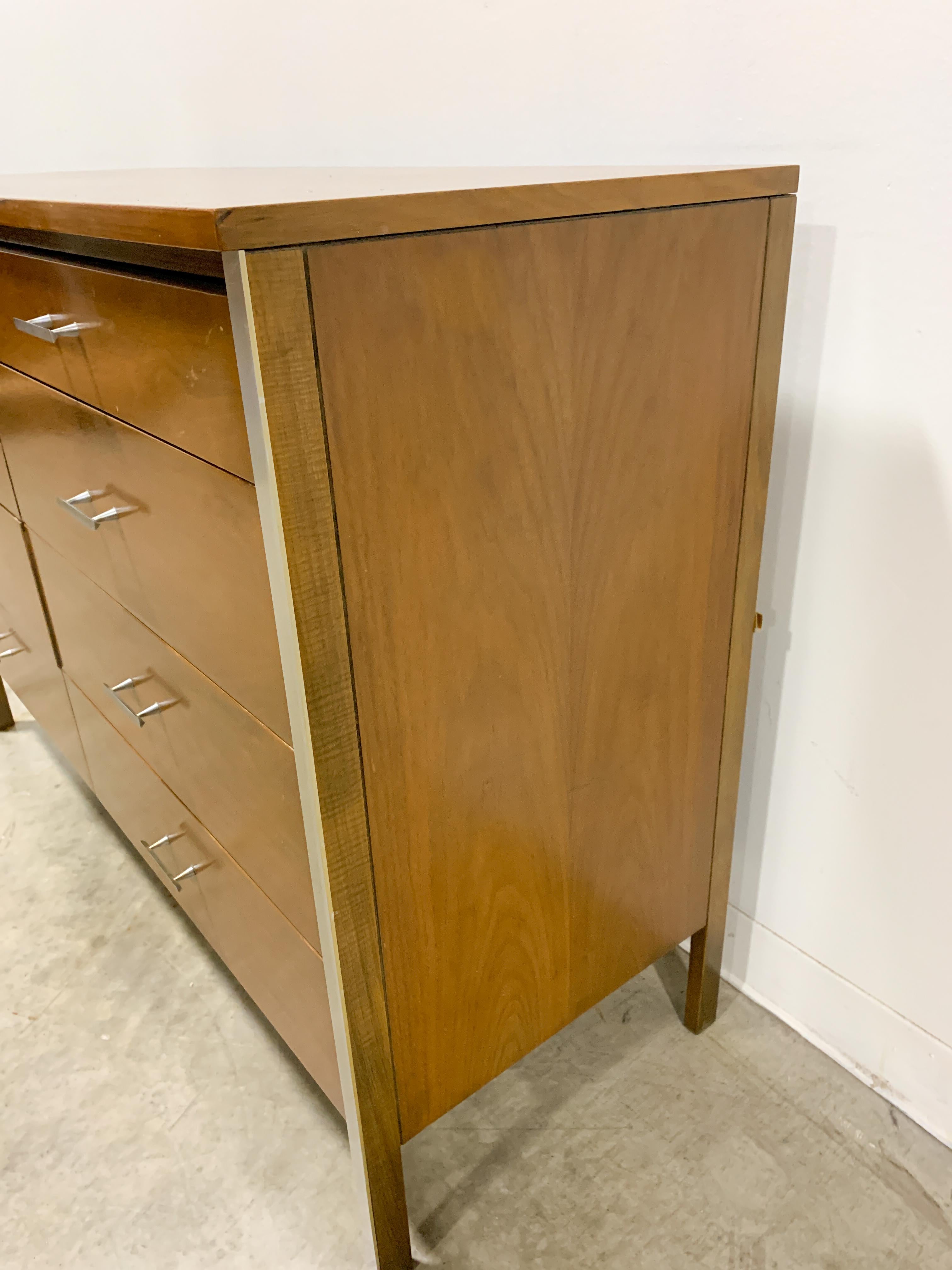 Short eight drawer dresser designed by Paul McCobb from the Linear line by Calvin Furniture. Walnut case with aluminum strips and cast aluminum pulls combine for a sharp modern look. This piece is in good original condition with occasional finish