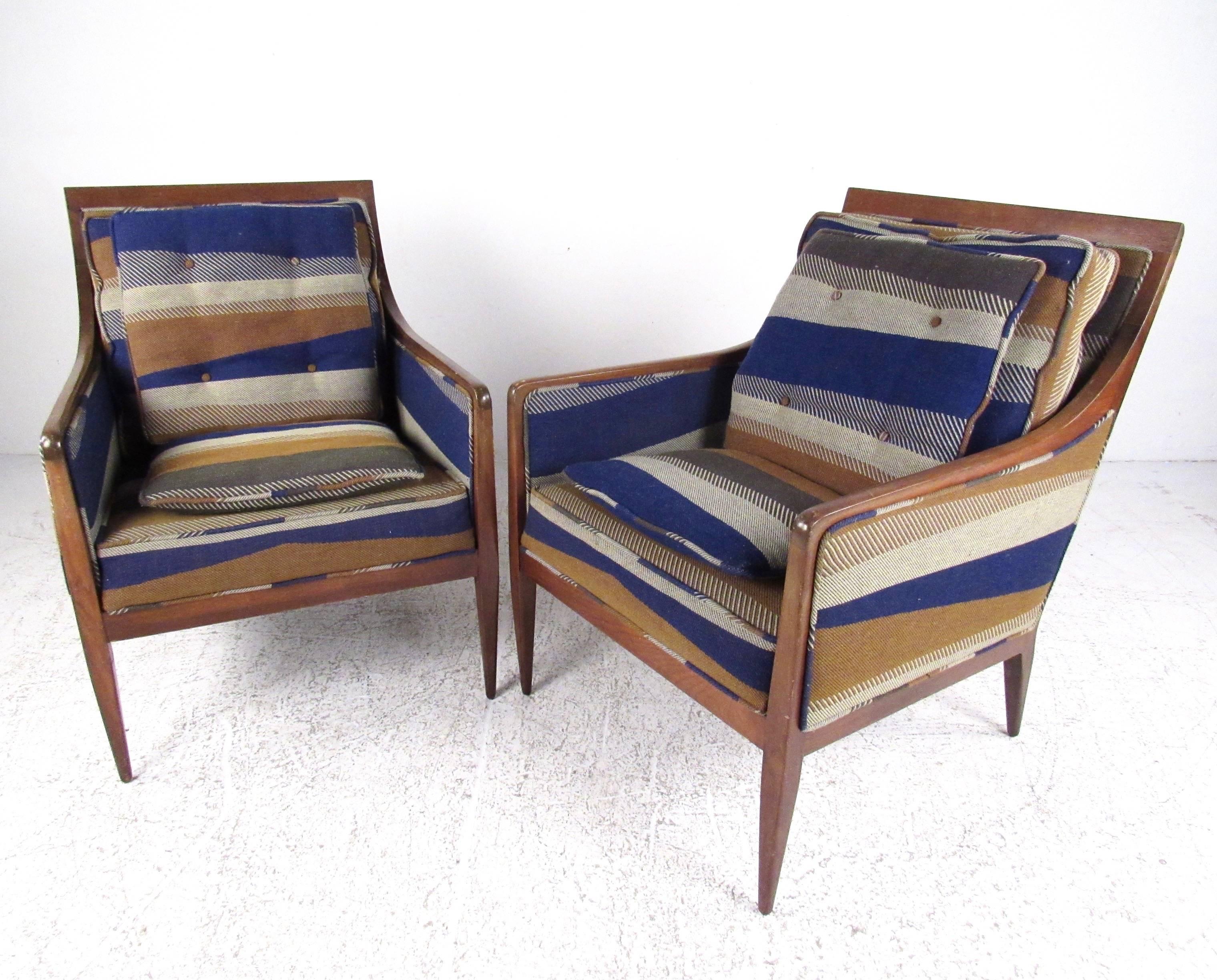 This stylish pair of midcentury lounge chairs by Paul McCobb for Calvin Group feature sturdy vintage walnut frames and unique original upholstery. The stylish shape of this designer pair of chairs makes them a comfortable and striking addition to