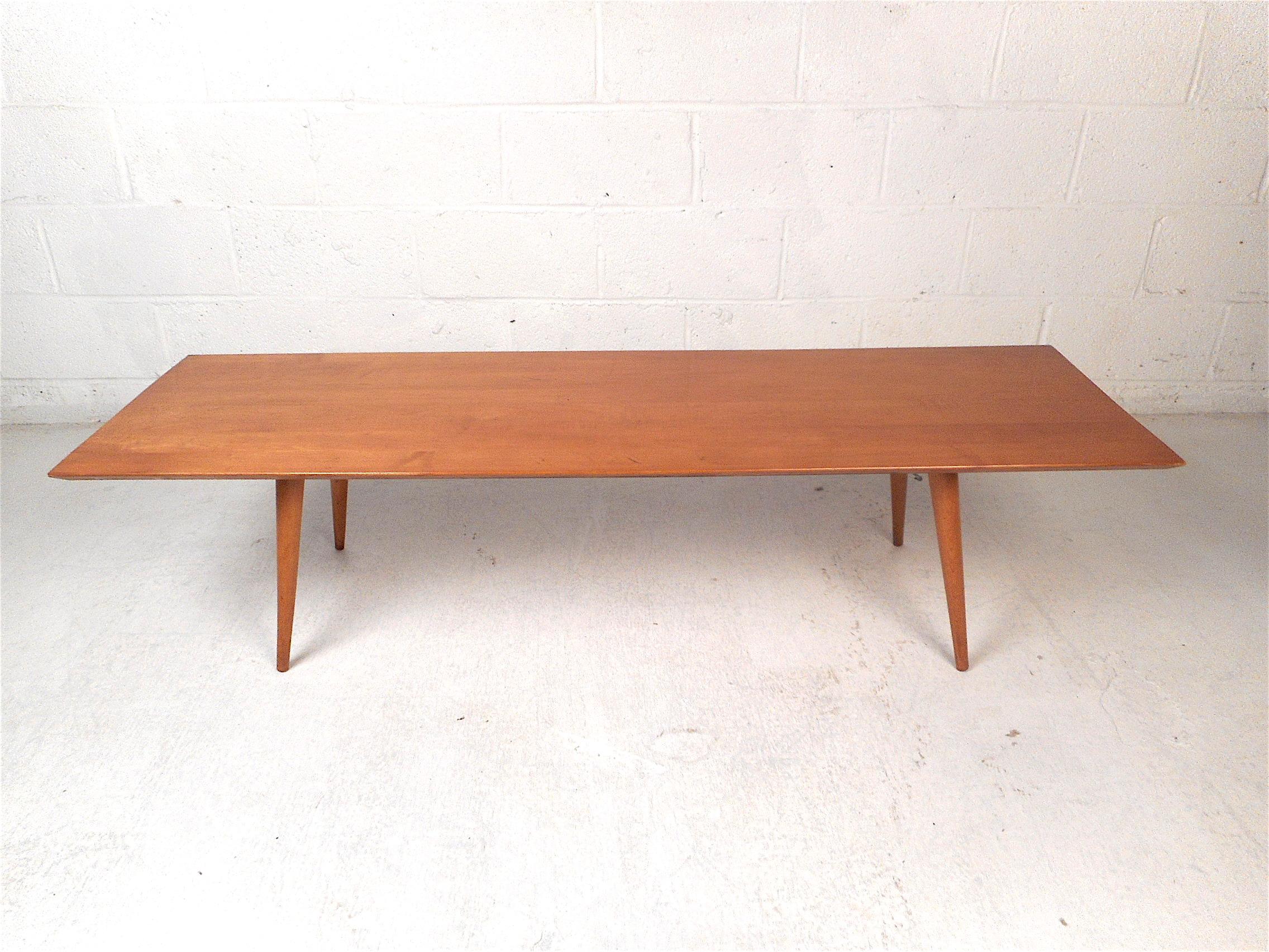 Stylish midcentury coffee table. Sturdy maple wood construction. Sleek, slim tabletop supported by splayed and tapered legs. Designed by Paul McCobb, circa 1960s. Please confirm item location with dealer (NJ or NY).