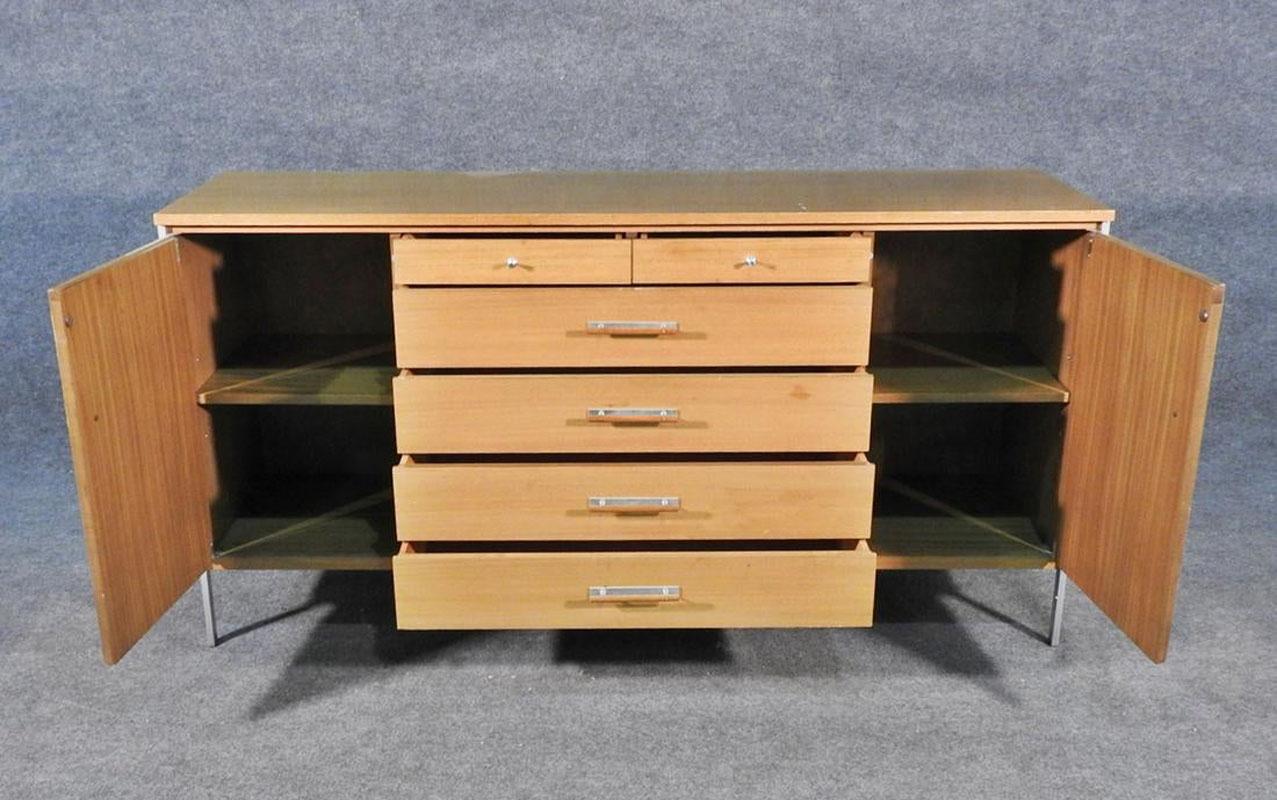 Metal legs and hardware. Blonde mahogany. Has 2 doors containing 1 shelf each. 6 drawers. Measures: 34 1/2