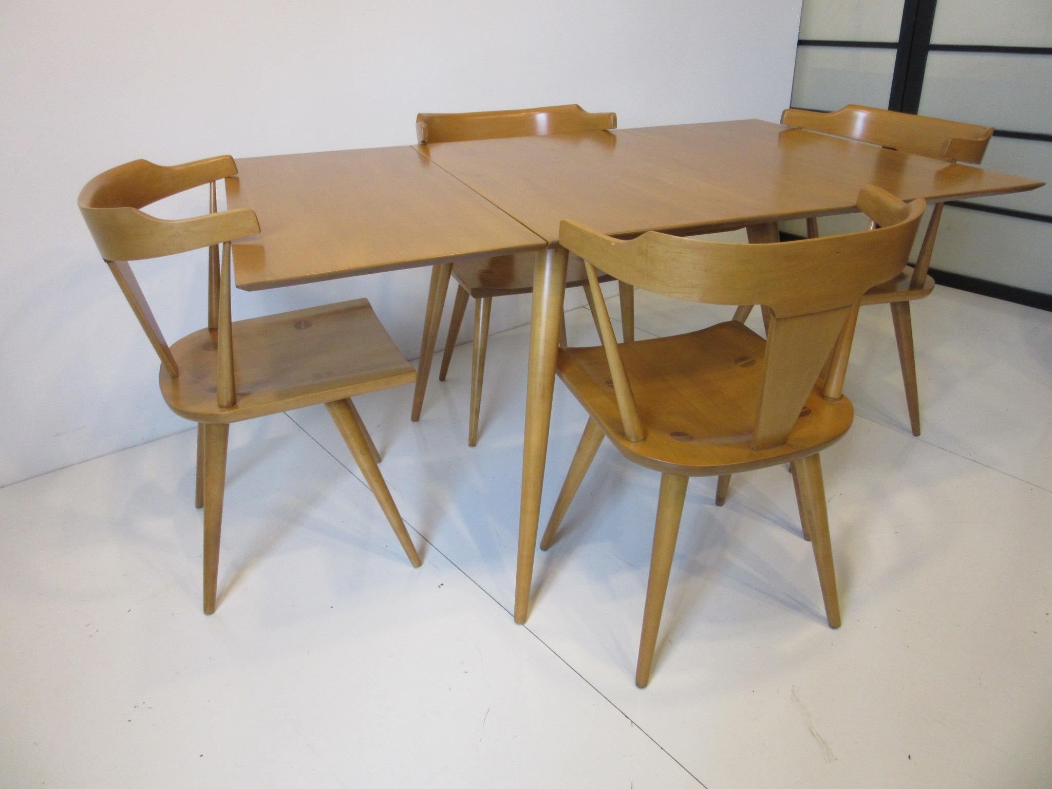 A five-piece Paul McCobb dining set including all solid maple drop-leaf table and four matching T-Back dining chairs with conical legs model # 1530. From the Planner Group collection a great midcentury design retaining the original manufactures