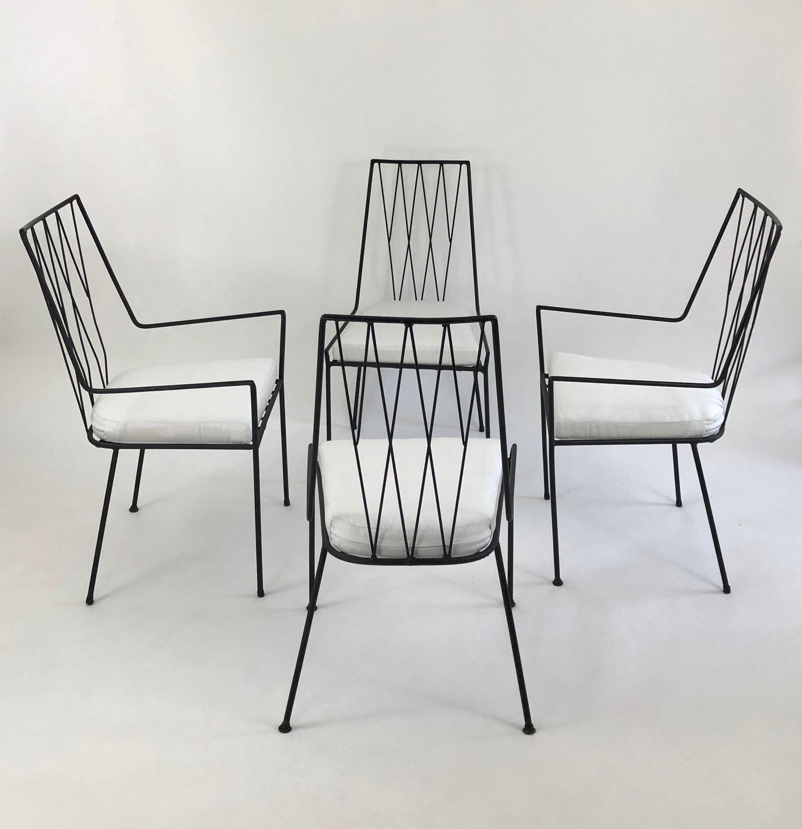 A Paul McCobb designed Pavilion Garden Furniture collection set of patio furniture, comprising a white milk glass table and four chairs in black wrought iron, with newly upholstered seat cushions in white Sunbrella with marine foam inserts. The set