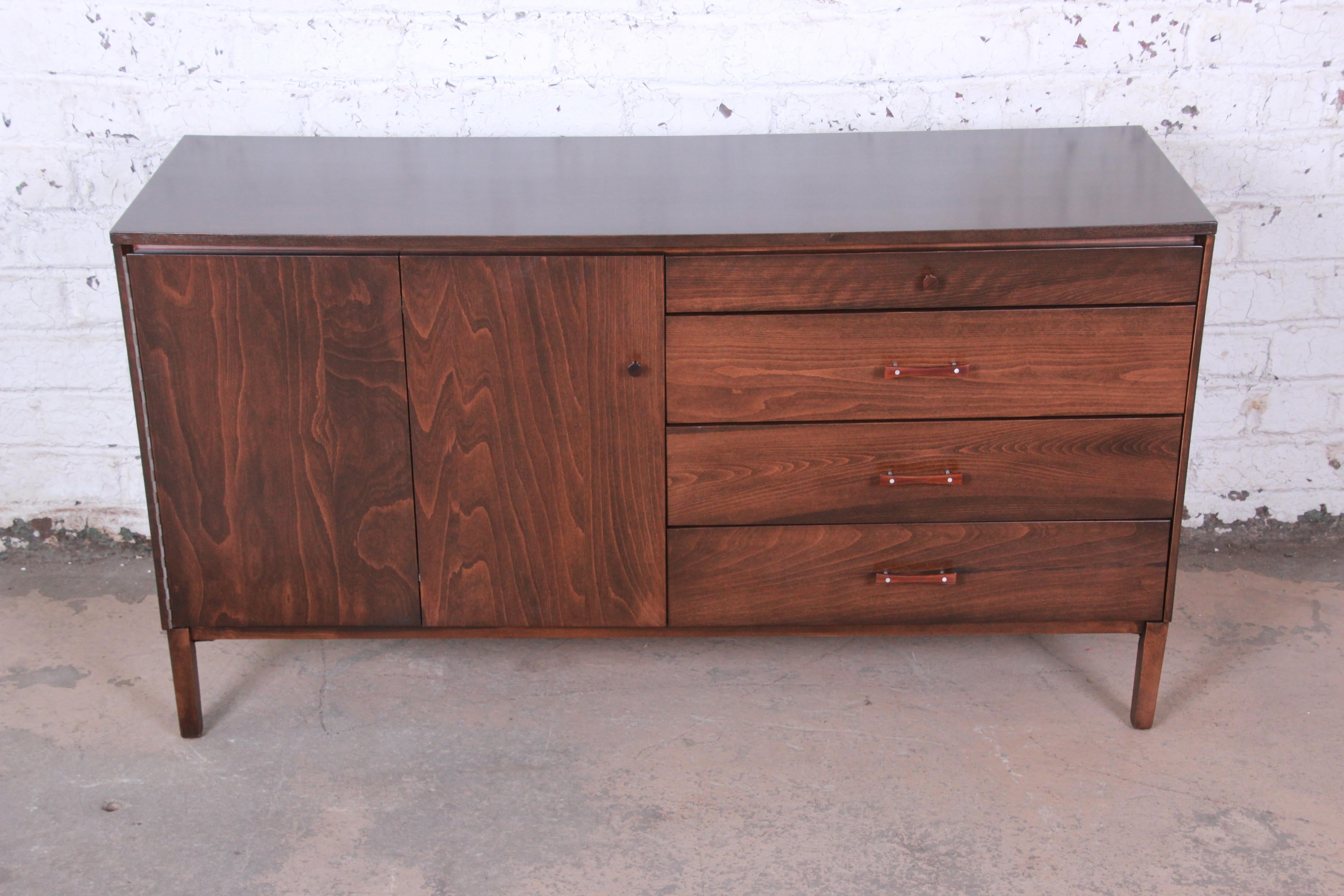 A rare and stunning Perimeter Group credenza by Paul McCobb. The credenza is newly refinished with rich stunning birch wood grain. The left side of the piece is a bi-fold door that opens up to an adjustable shelf. The right side has four drawers