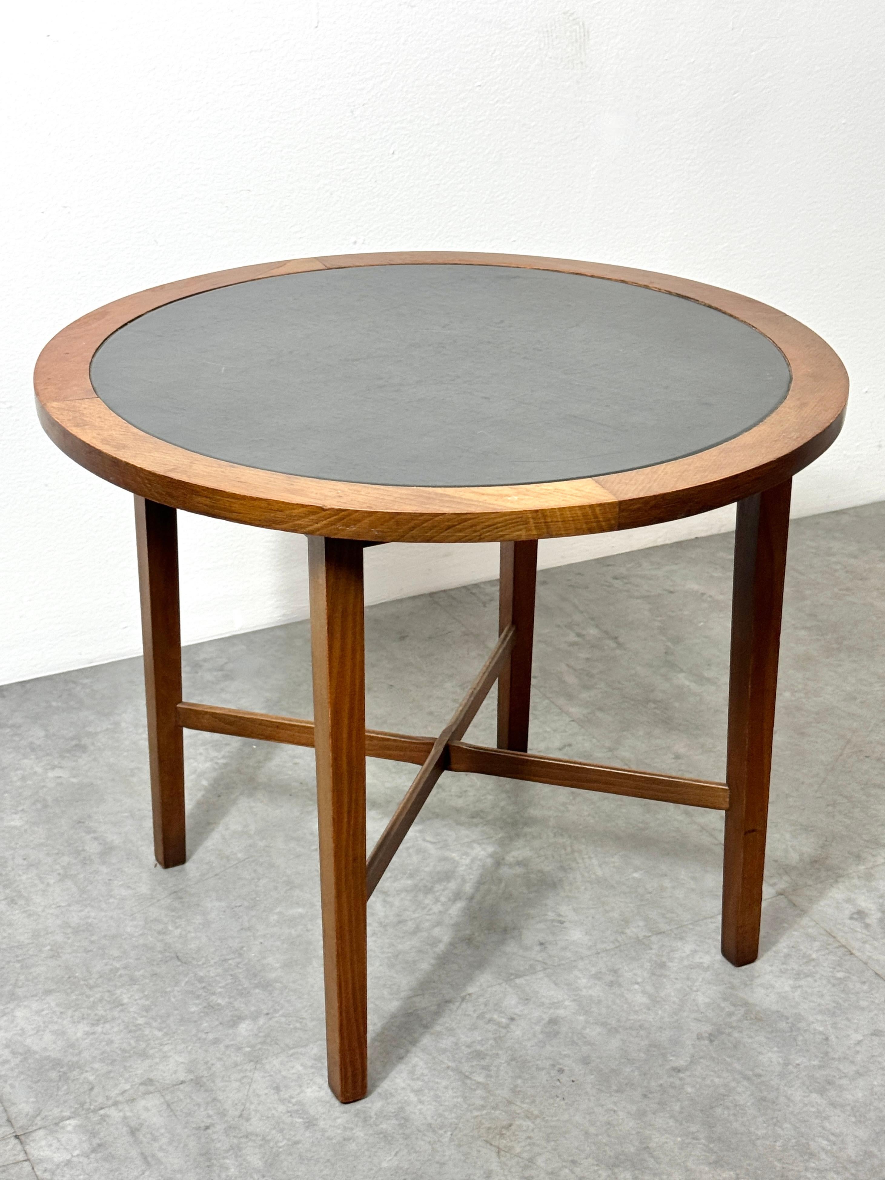 A seldom seen Mid Century modern end table designed by Paul McCobb for Winchendon circa 1950s

Model 2682 from the Perimeter group in walnut with X base and inset black leather surface

21 inch diameter
17.5 inch height

Marked to underside with a