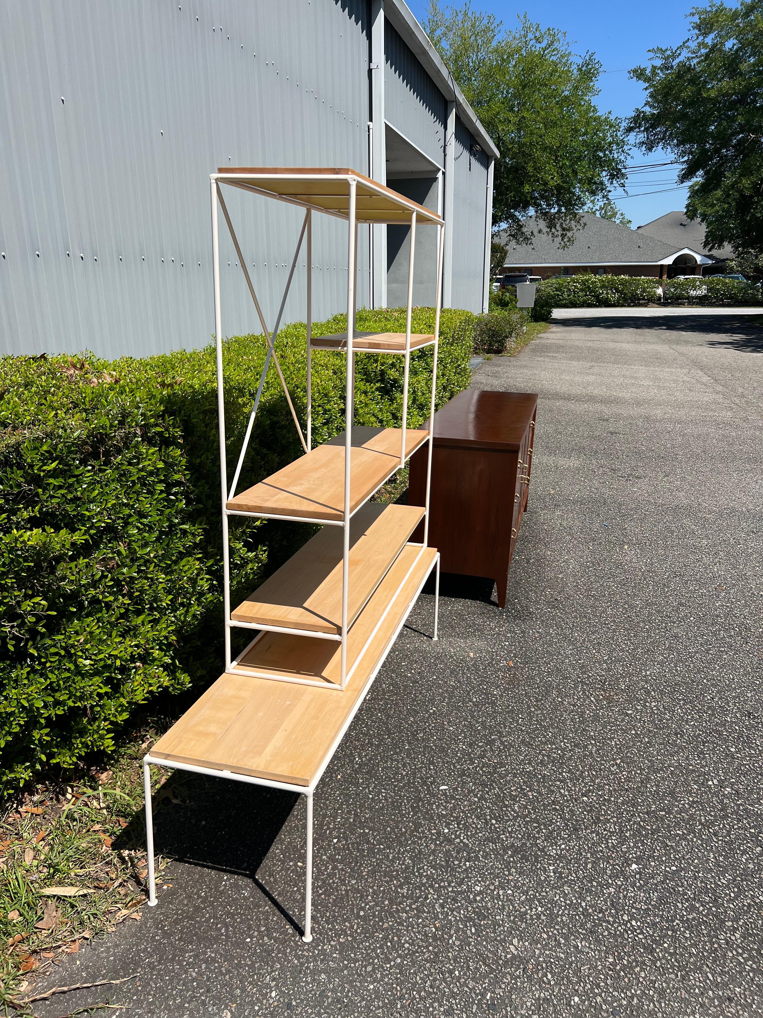 A two piece satin white iron and light toned maple wood bookcase / etagere designed by Mid Century icon Paul McCobb . Sitting on a matching bench styled platform manufactured by the Winchendon furniture company from the Planner group collection .  