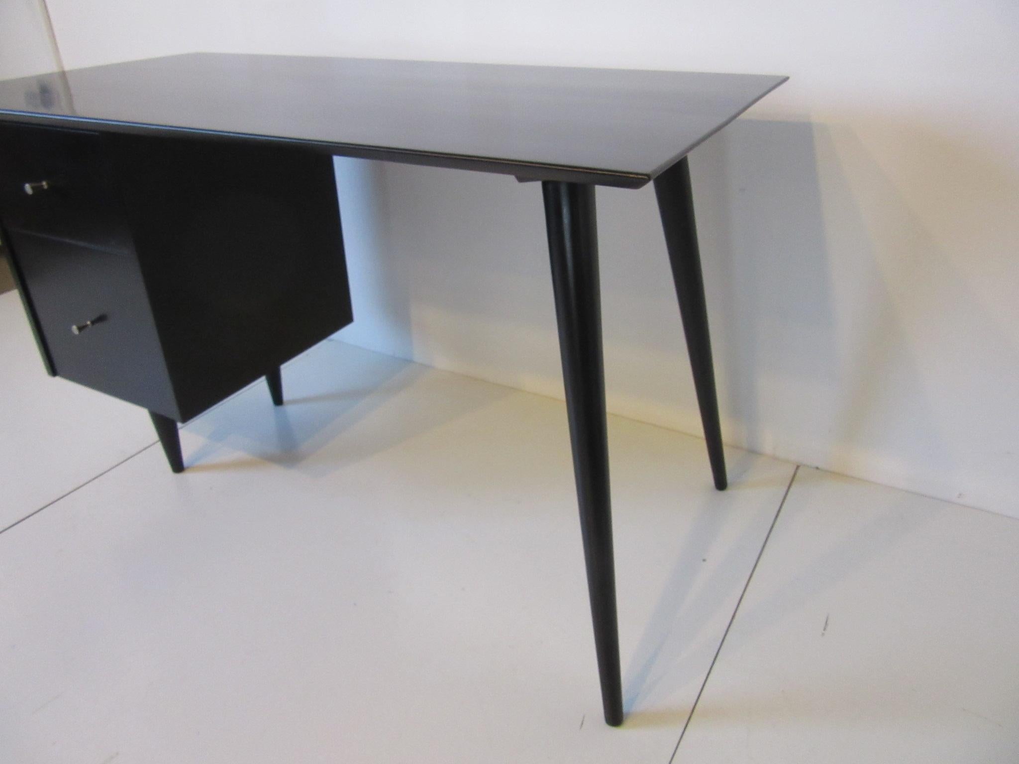 A satin black McCobb desk with splay leg design to one end and two drawers with the T pulls, from the Planner Group collection for the Winchendon Furniture Company.