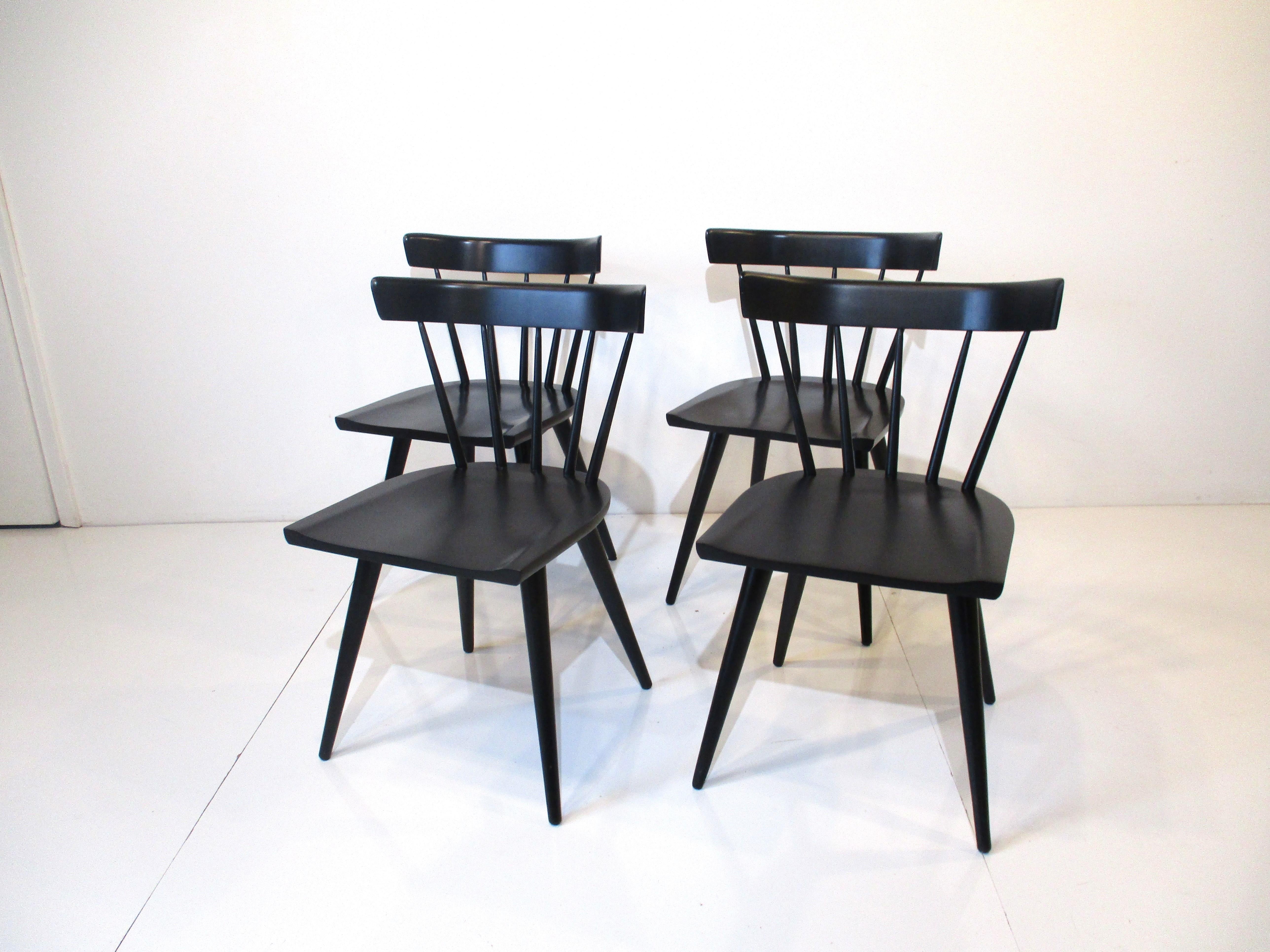 A set of four satin black spindle back dining chairs by Paul McCobb from the Planner Group Collection manufactured by the Winchendon Furniture company. Well made of solid maple wood with a simple design that works with many types of interiors and