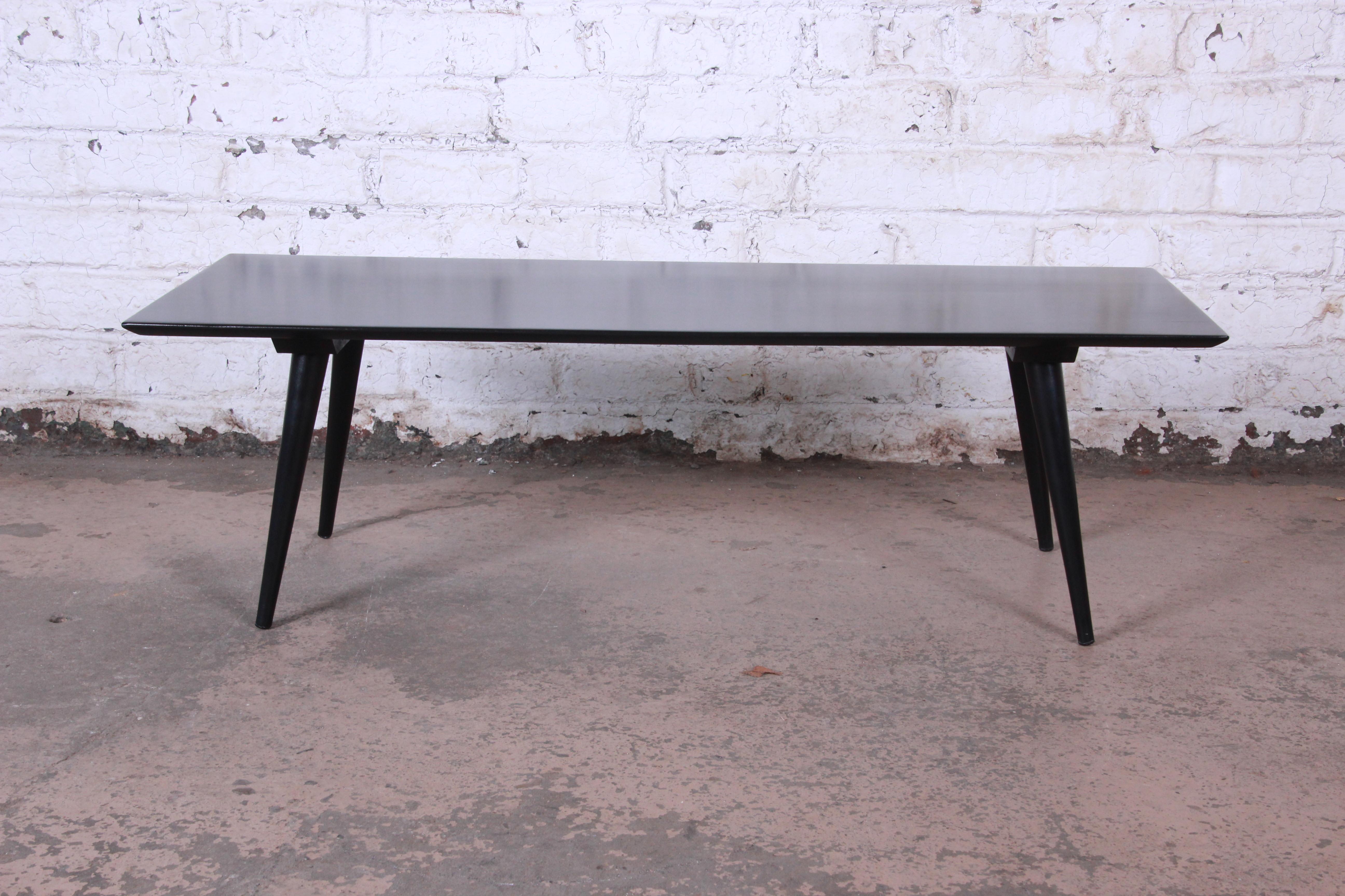 A sleek and stylish Mid-Century Modern coffee table designed by Paul McCobb for his Planner Group line for Winchendon Furniture. The table features solid birch construction with a black lacquered finish and nice tall tapered legs. An excellent