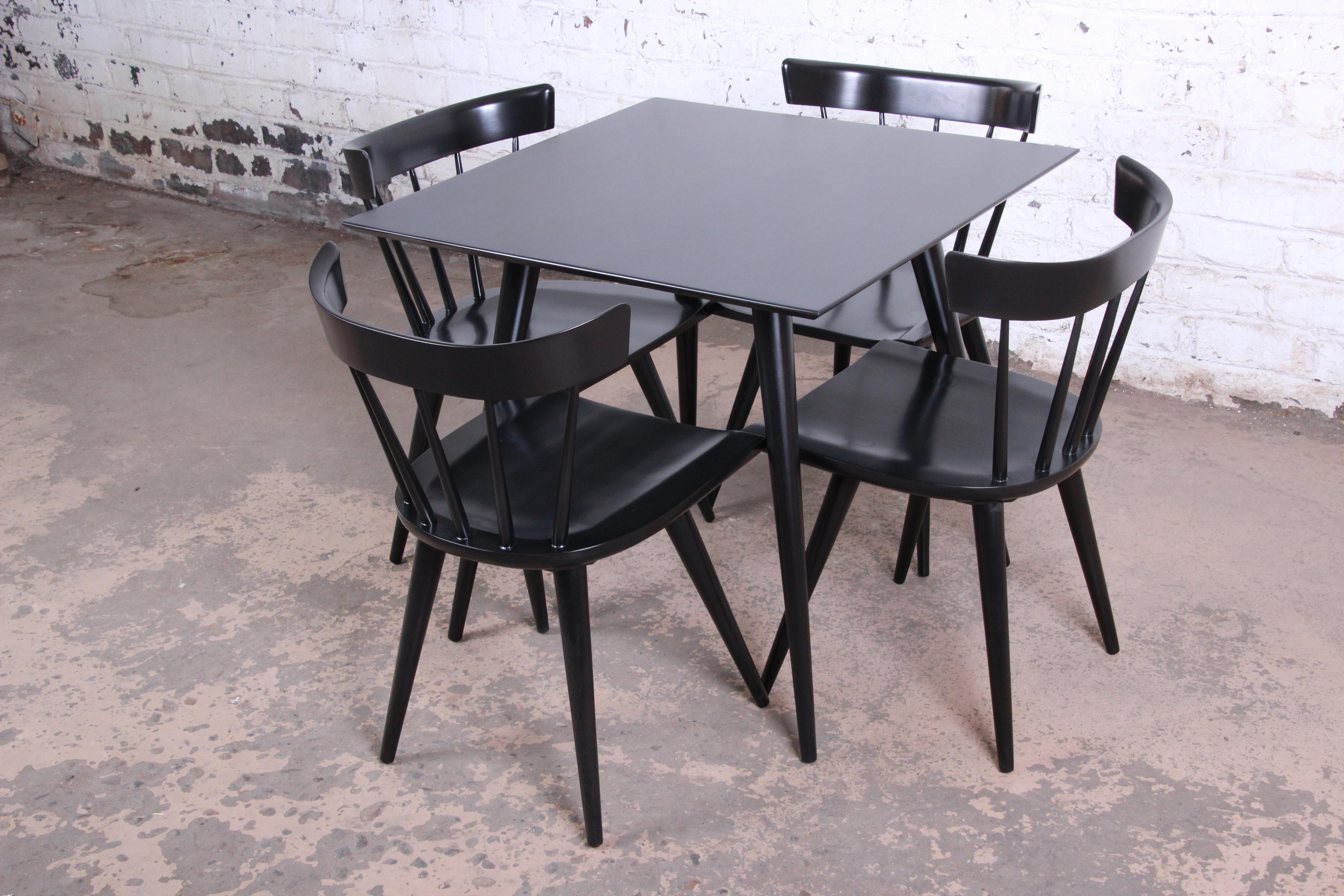An exceptional Mid-Century Modern square dining or game table with four chairs designed by Paul McCobb for his Planner Group line for Winchendon Furniture. The table features a gorgeous ebonized finish with tall tapered legs, a rare piece from this