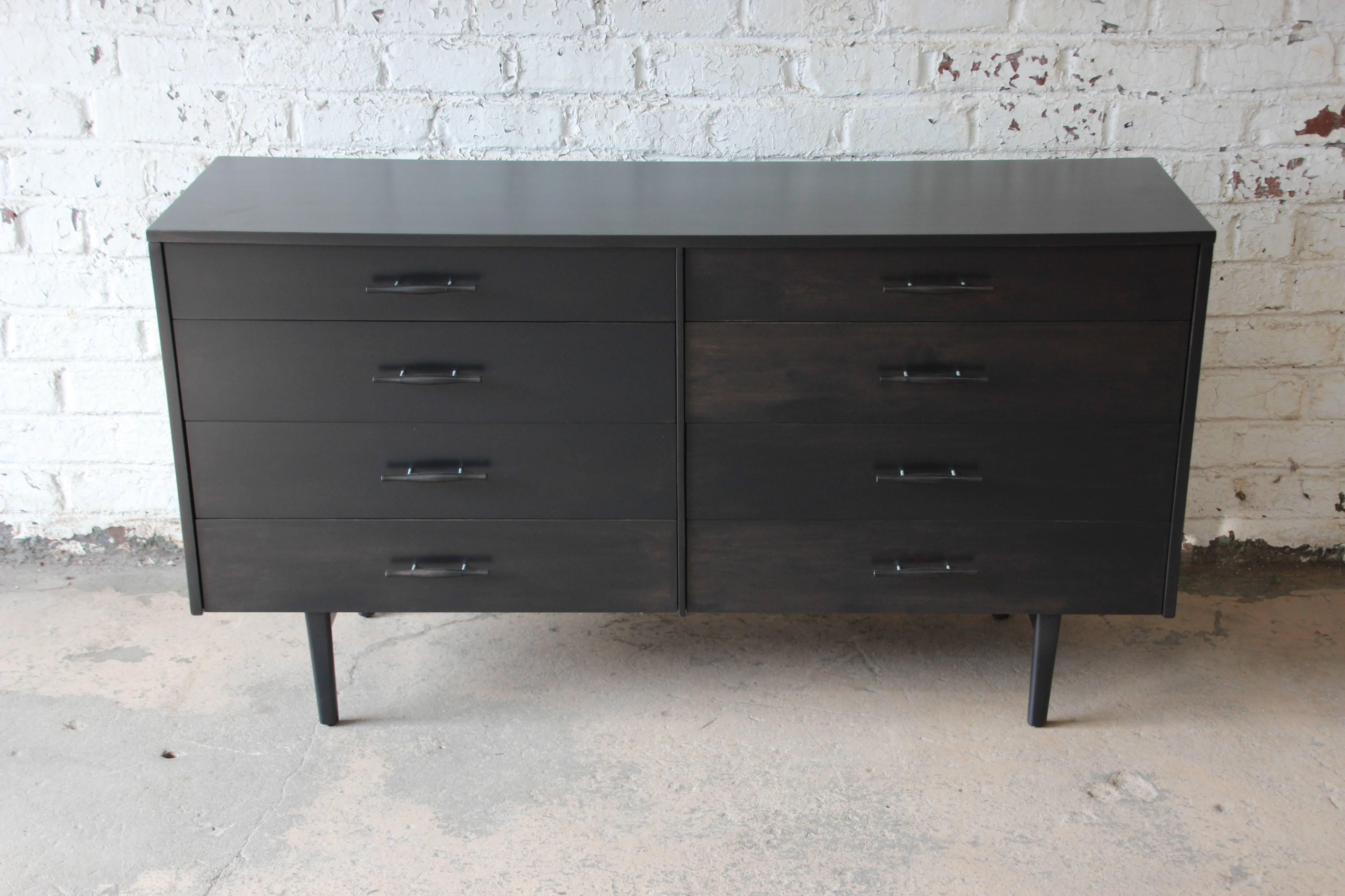 Offering a fantastic Paul McCobb ebonized eight-drawer dresser of credenza for planner group. This newly refinished piece has eight smooth sliding drawers with aluminum and ebonized wood pulls. It has unique slanted tapered legs and is a rare design