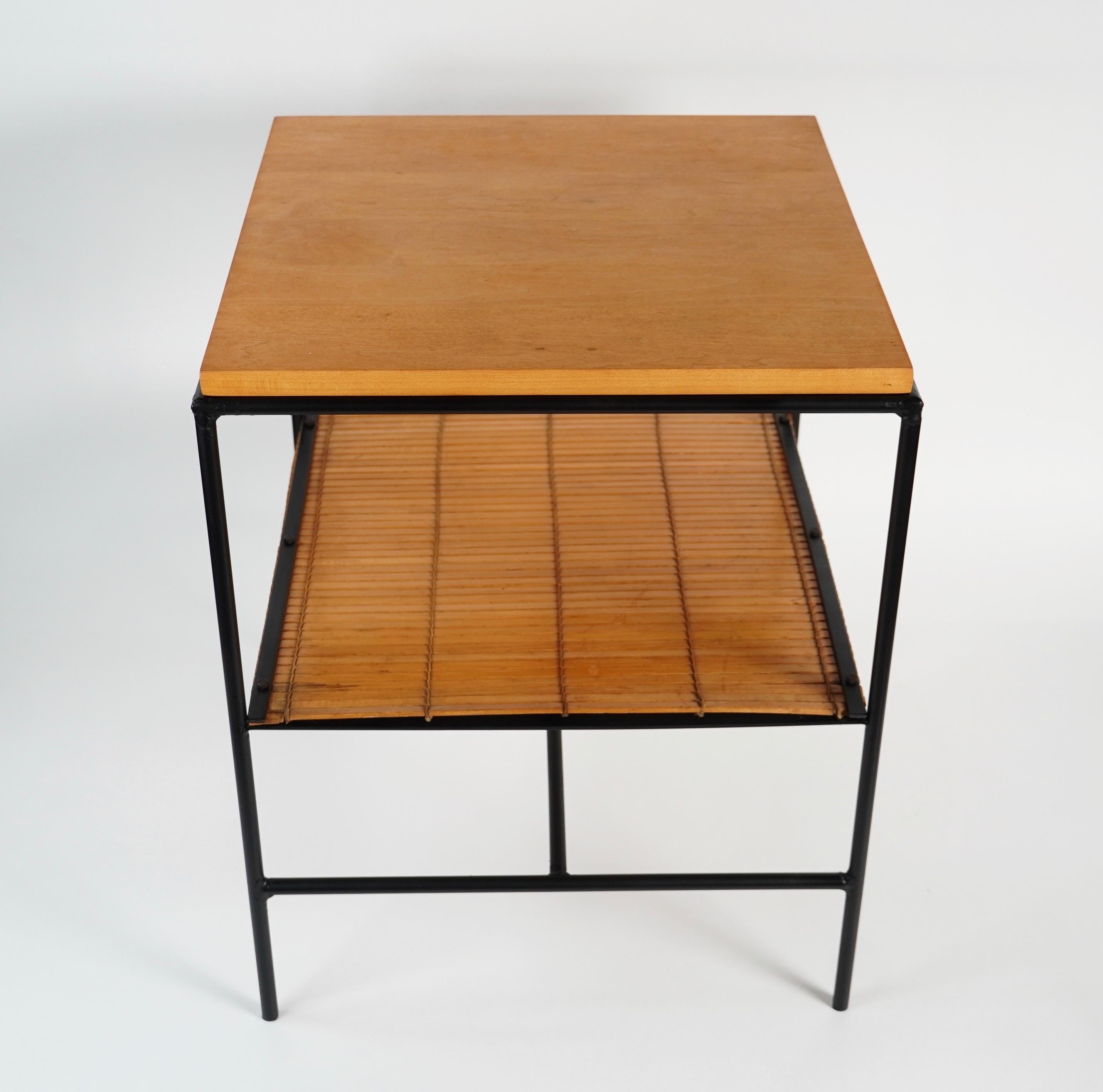 American designer Paul Winthrop McCobb (1917-1969) Planner Group side table with a black iron frame, woven bamboo bottom shelf and a square maple top. The blend of these materials in its construction gives the table a refined understated appearance.