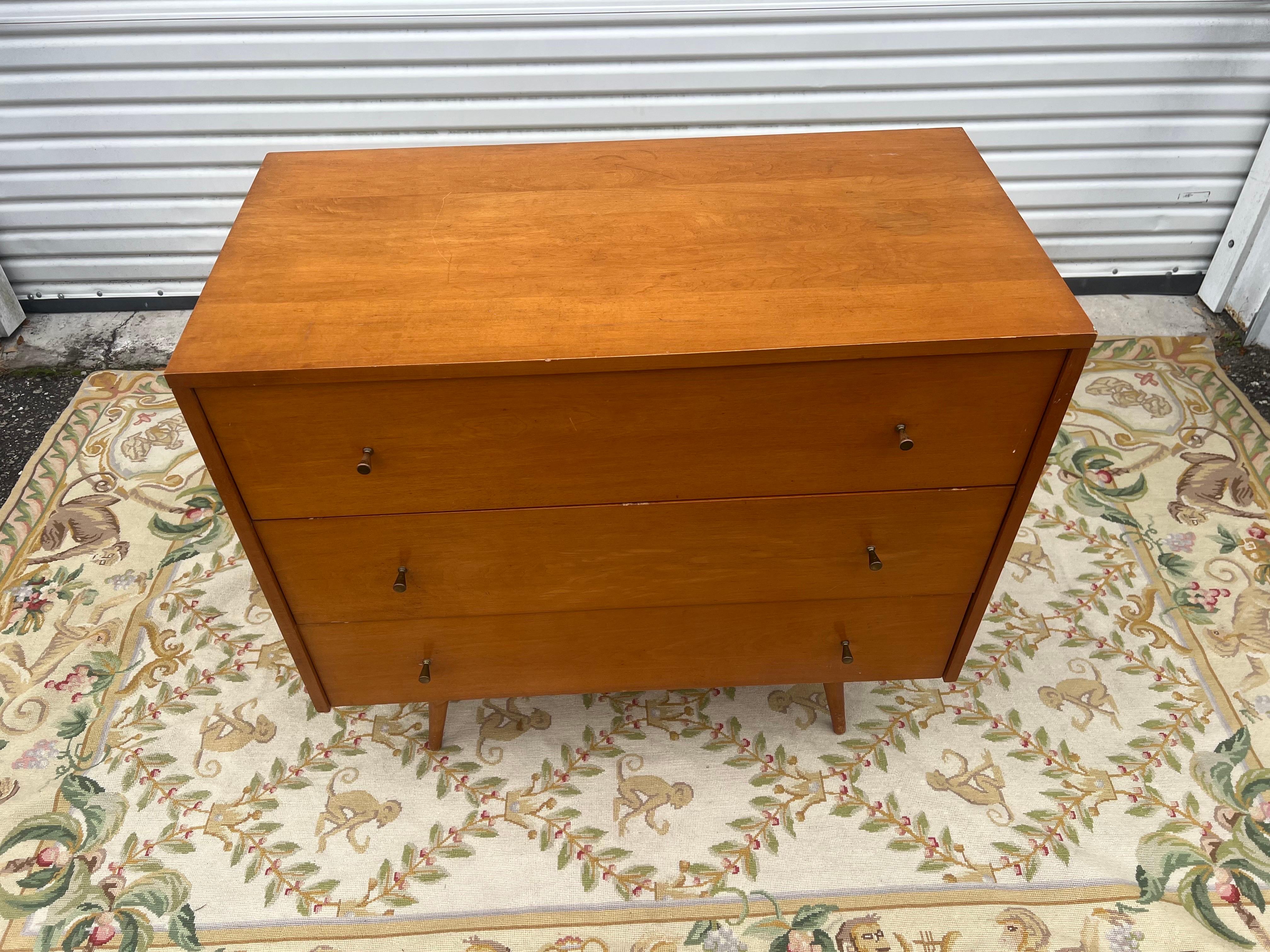 USA, circa 1950s. A great little chest from Paul McCobb’s Planner Group. Features maple construction with three large drawers, splayed conical legs, and signature brass hourglass pulls. This piece is in it’s original finish, which is hard to find.