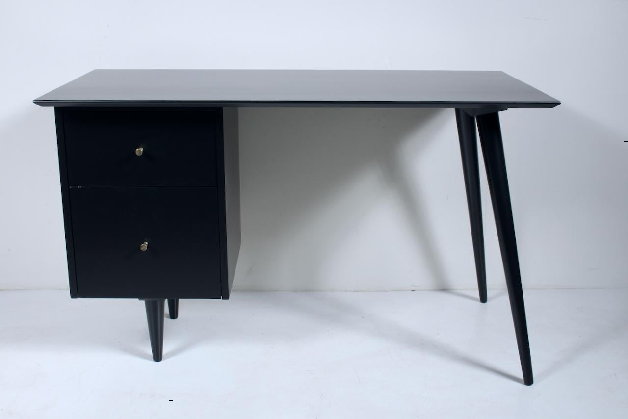 Classic Paul McCobb Planner Group for Winchendon Black Lacquer Desk. Featuring a rectangular frame with large smooth solid wood work surface, 2 spacious drawers, with 4 threaded dowel legs and original Brass pulls. Produced in Winchendon,