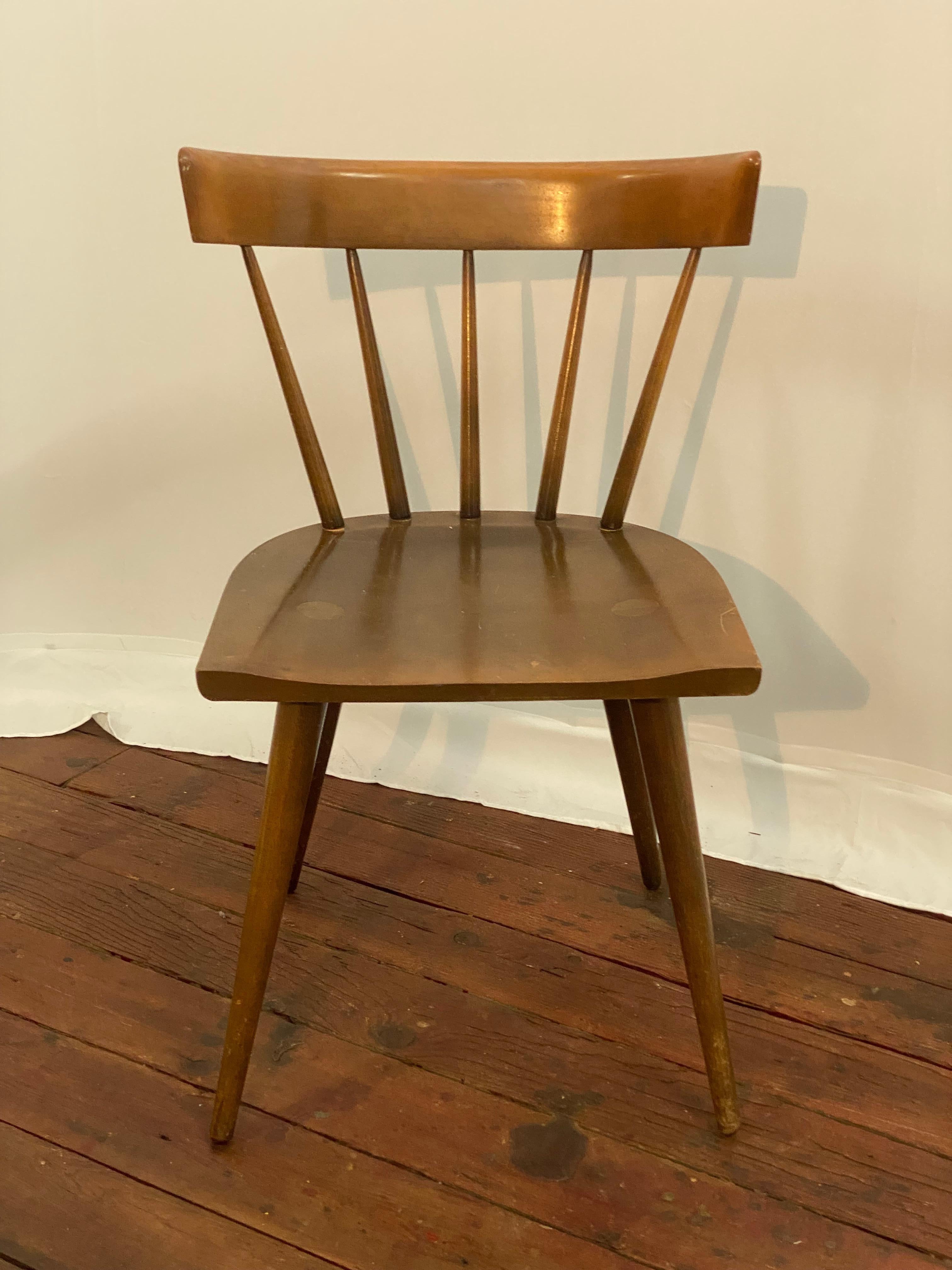 The classic Paul McCobb Planner Group spindle back side chair. Constructed of solid maple Planner Group for Winchendon. Circa 1950. The chair features a curved back with flared spindle supports, dowel and tapered legs. The seat is adorned with the