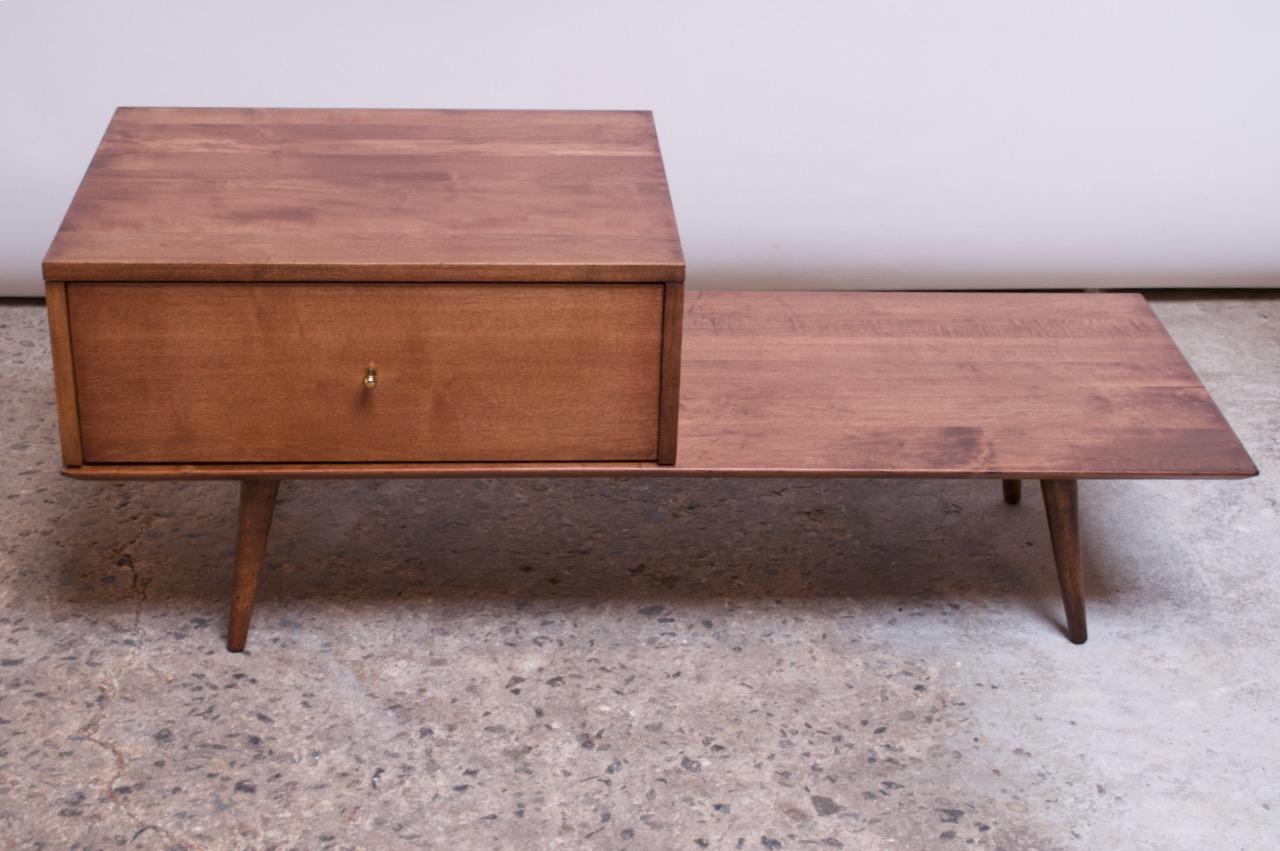 Stained-maple single drawer cabinet on bench designed in the 1950s by Paul McCobb for Winchendon Furniture. Cabinet features a sculptural brass pull, and the minimal base is supported by turned, tapered legs.
Versatile design: the module on top can