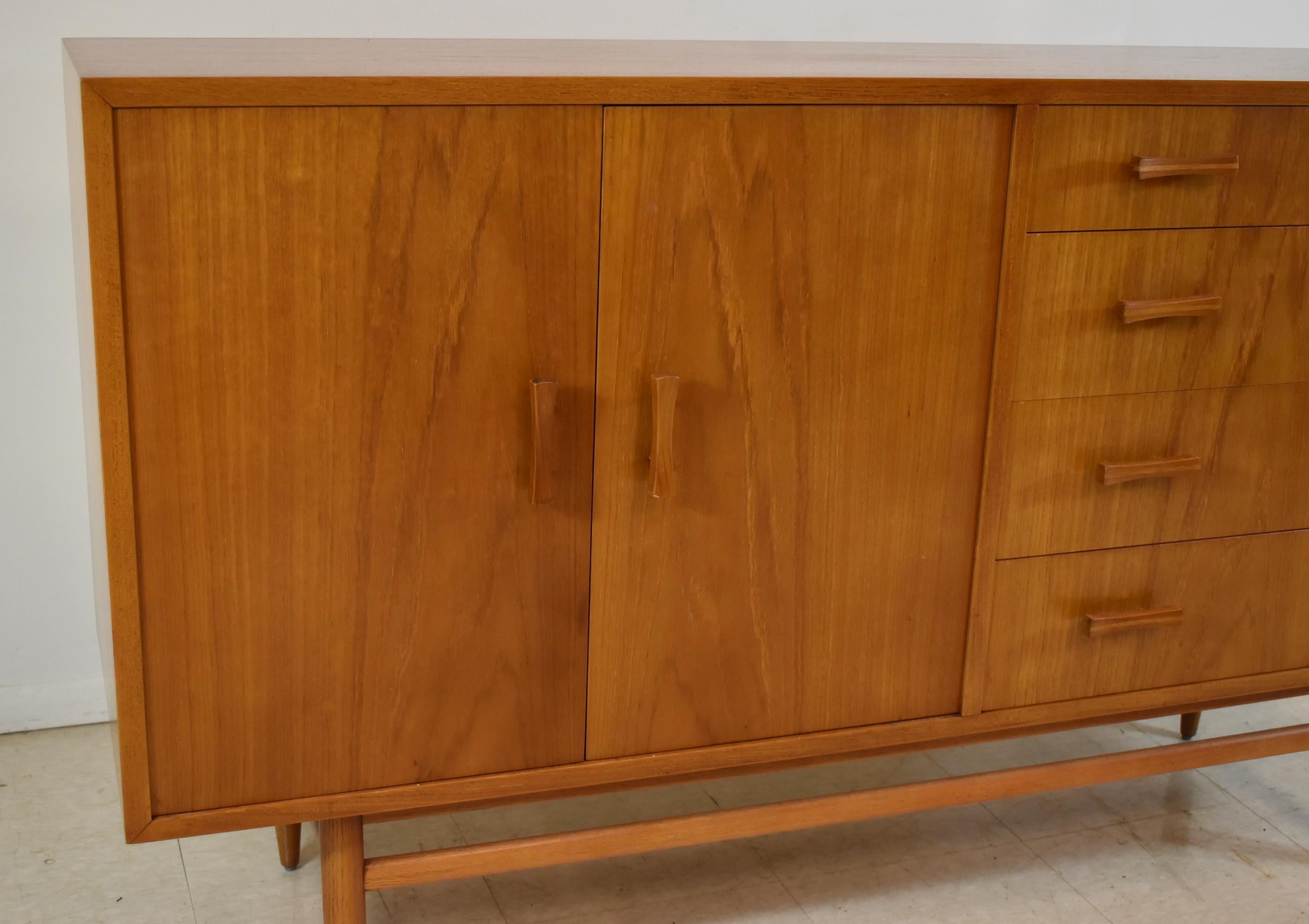 Paul McCobb planner group style credenza made of teak wood with bow tie shaped handles, contains 4 dovetailed drawers, adjustable shelving. In excellent condition. Dimensions: 60