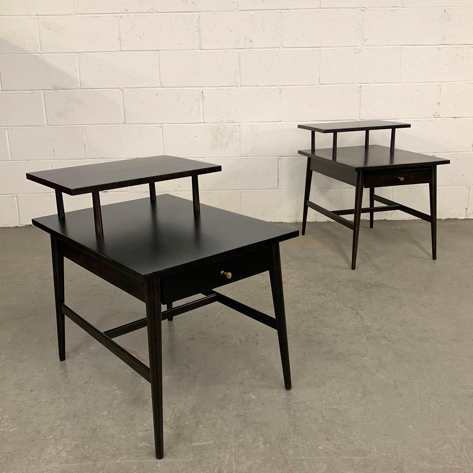 Pair of ebonized maple, step end tables with drawers by Paul McCobb, Planner Group for Winchendon, with signature hourglass brass pulls. The height of the lower tier is 19.5 inches.