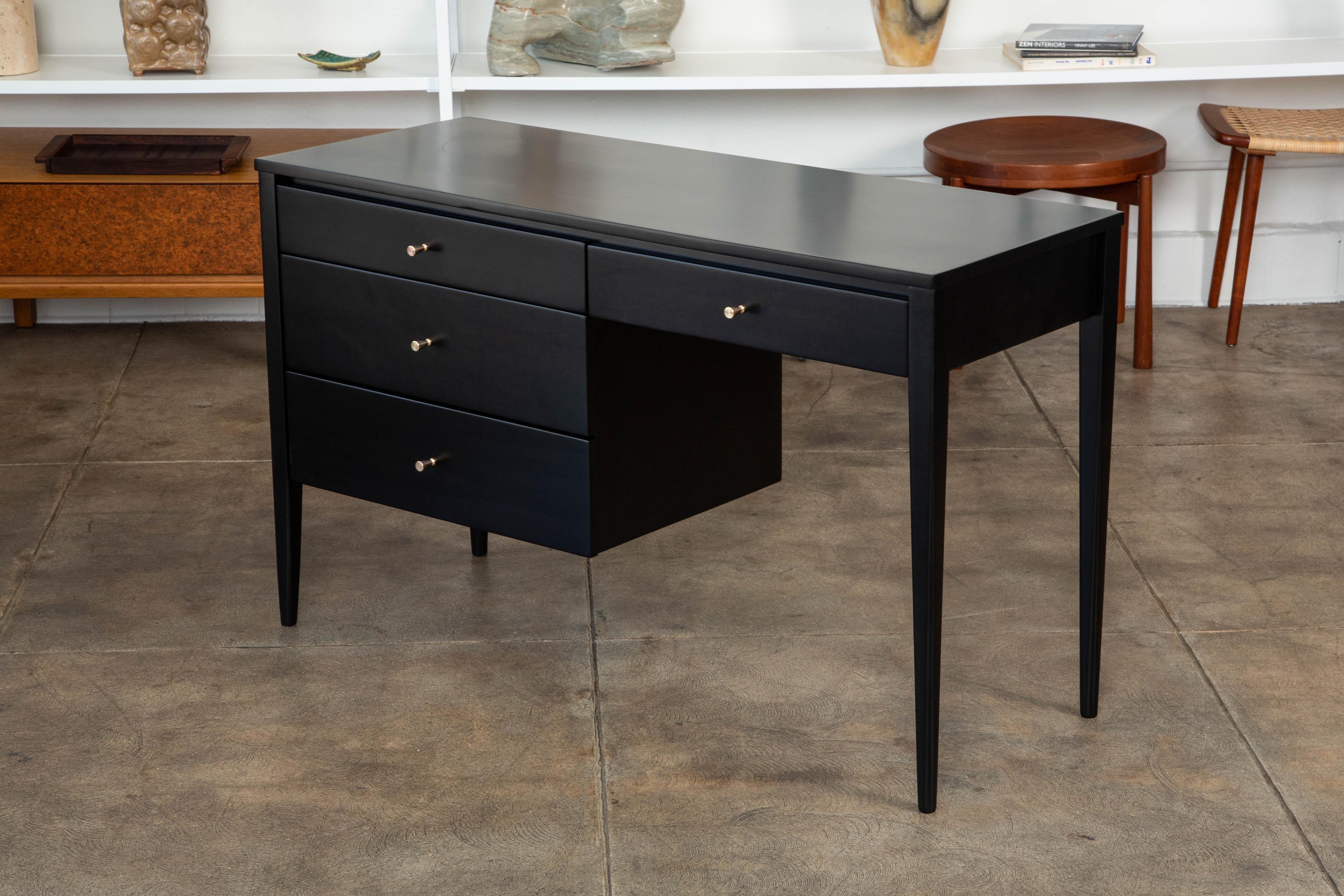 Paul McCobb writing desk from the Planner Group collection for Winchedon, circa 1950s. The ebonized maple desk features four drawers with solid brass knobs. There is a single drawer underneath the leg clearance with a three-drawer stack on the left