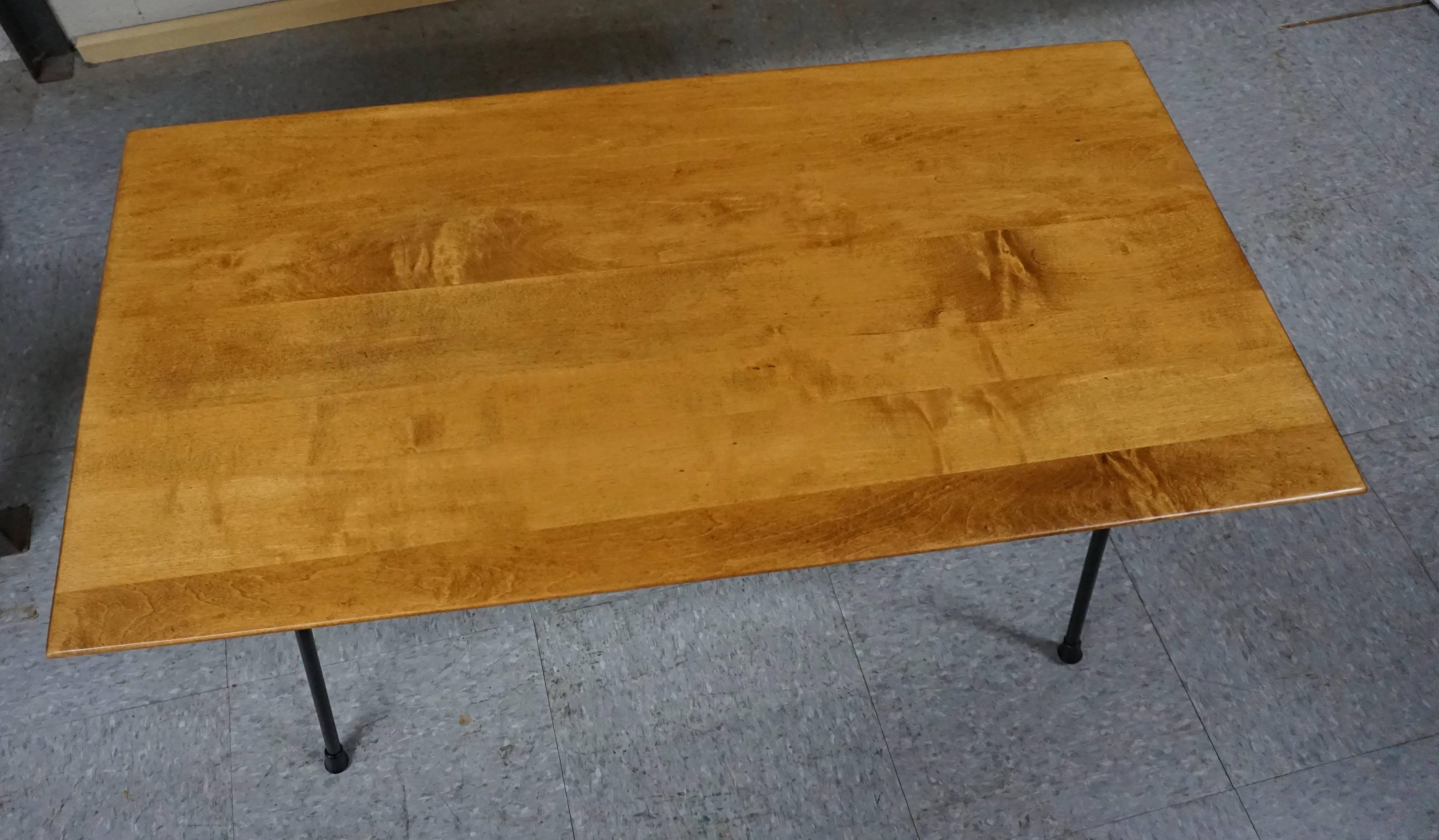 Wood top coffee table with fresh black paint on the base. Top has a warm toned finish, with just a few small naturally occurring impressions in the wood. Rubber feet are all intact.