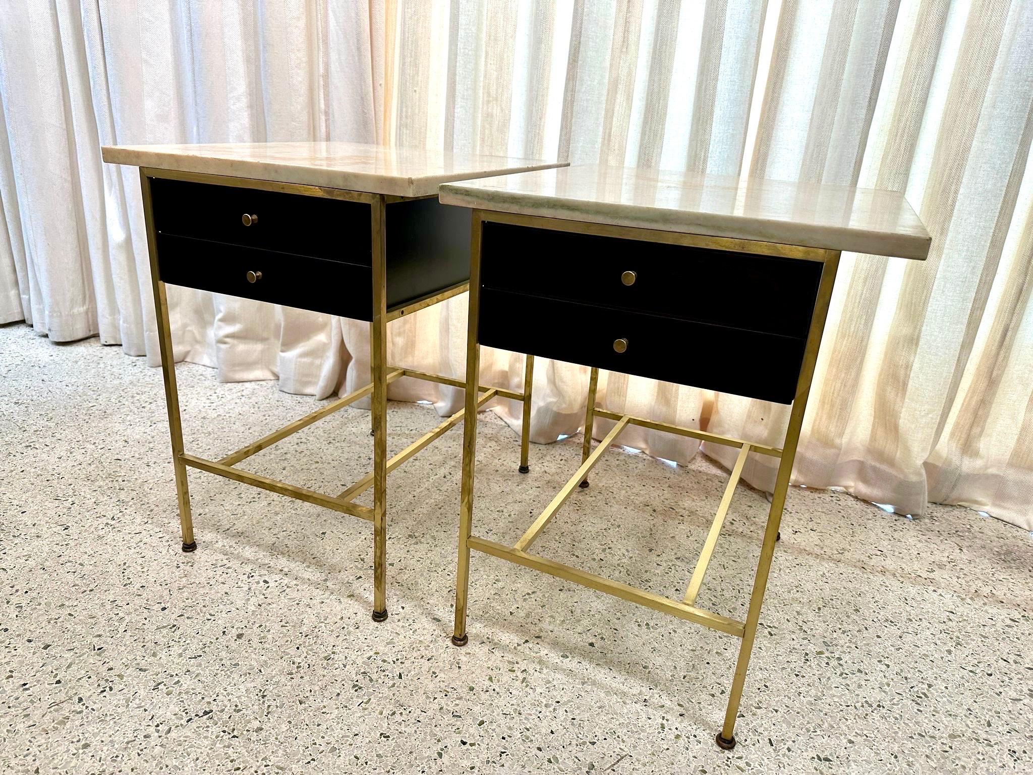 Rare pair of Paul Mccobb side tables retaining the original marble tops. Part of the Irwin Collection by Calvin Furniture Co.. McCobb employs a wonderful mix of dark brown Mahogany and brass.

The wood two-drawer case is suspended in an