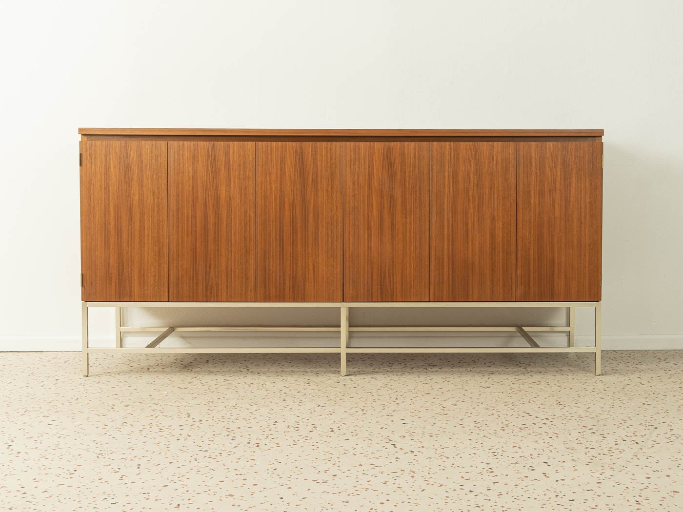 Very rare sideboard from the 1950s by Paul McCobb for WK Möbel. Corpus in walnut veneer with two shelves, two folding doors and squared steel base frame.

Quality features:
- Very high-quality materials
- Good workmanship
- Made in Germany.