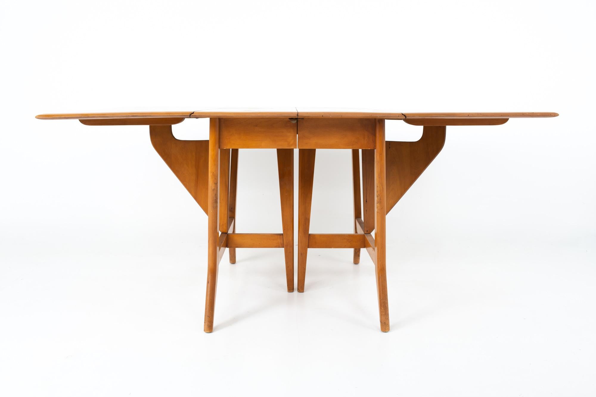 Mid Century drop-leaf dining table.
Table measures: 63.25 wide x 42 deep x 29 high; each leaf measures 10 inches wide

This piece is available in what we call restored vintage condition. Upon purchase it is fixed so it’s free of watermarks, chips or