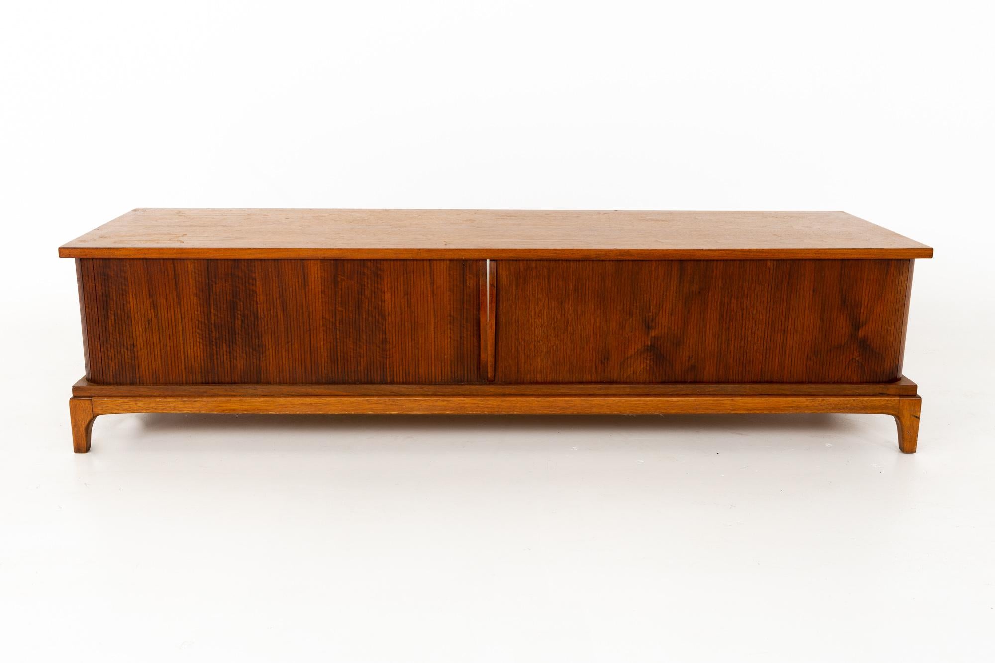 Paul McCobb style Lane rhythm mid century walnut tambour door coffee table

This coffee table is 64.75 wide x 19.25 deep x 16 inches high

All pieces of furniture can be had in what we call restored vintage condition. That means the piece is