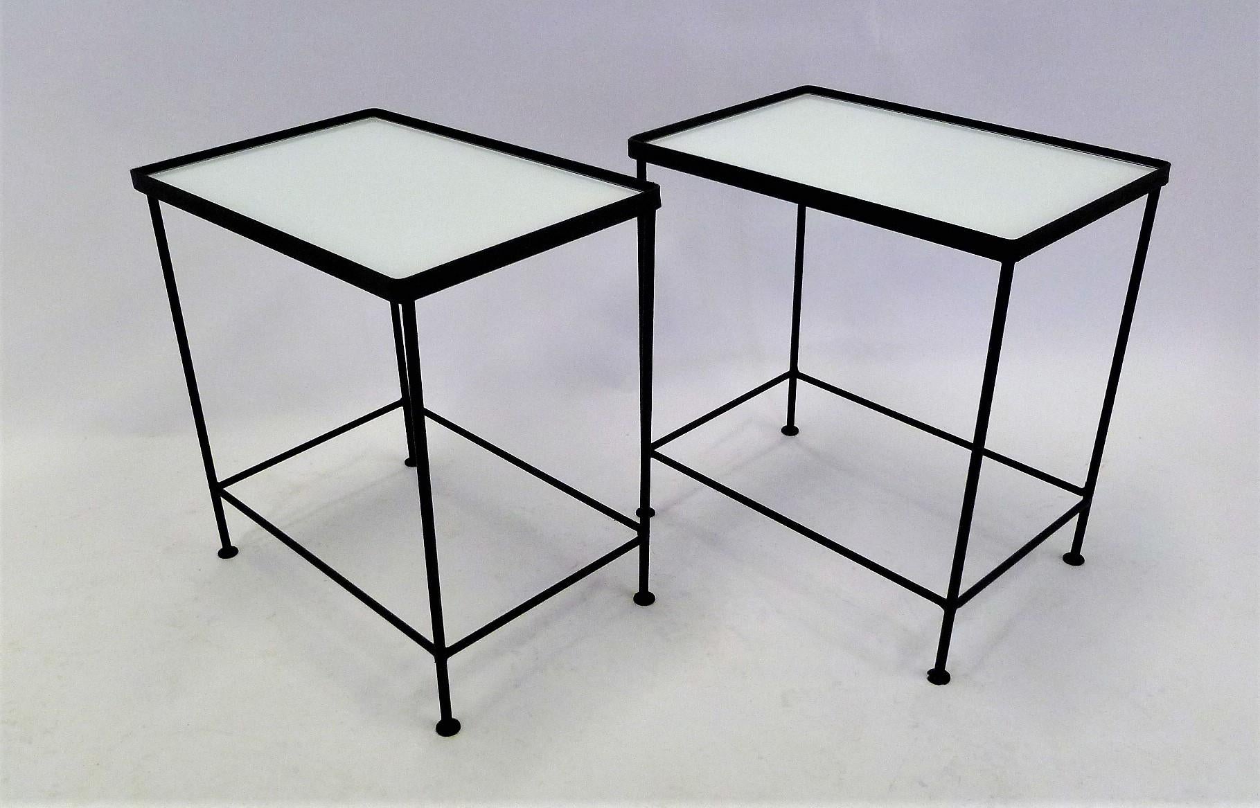 A pair if black iron and glass occasional tables in the unadorned, purity of form and line, midcentury style of Paul McCobb, especially his tables for Furnwood Corp, 1950s. Each with a very utile form to easily move around to where needed. With a
