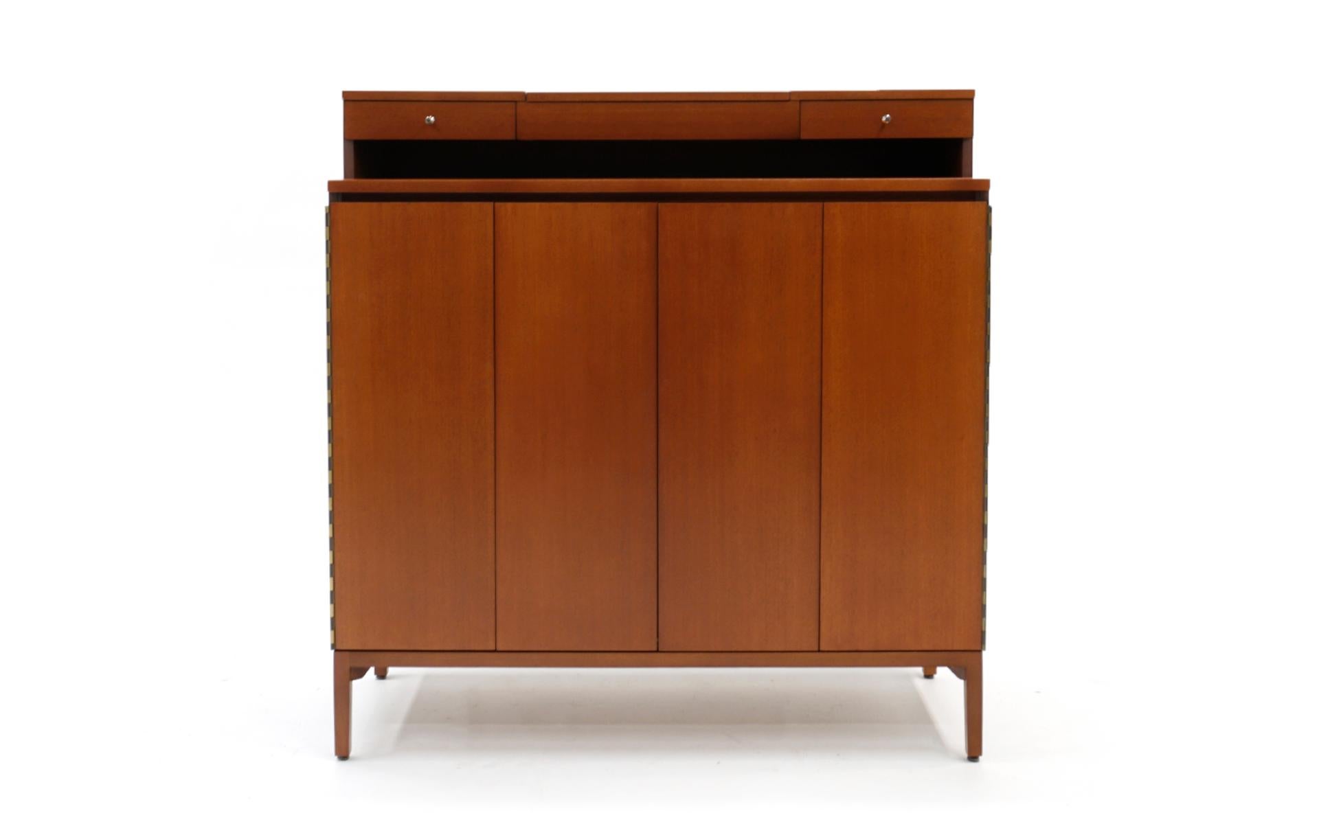 Tall chest / dresser designed by Paul McCobb for the Irwin collection produced by Calvin. Bi-fold doors reveal 18 slides out shelves on one side and 5 drawers of various sizes on the other. The upper portion has built in jewelry drawers and a lift