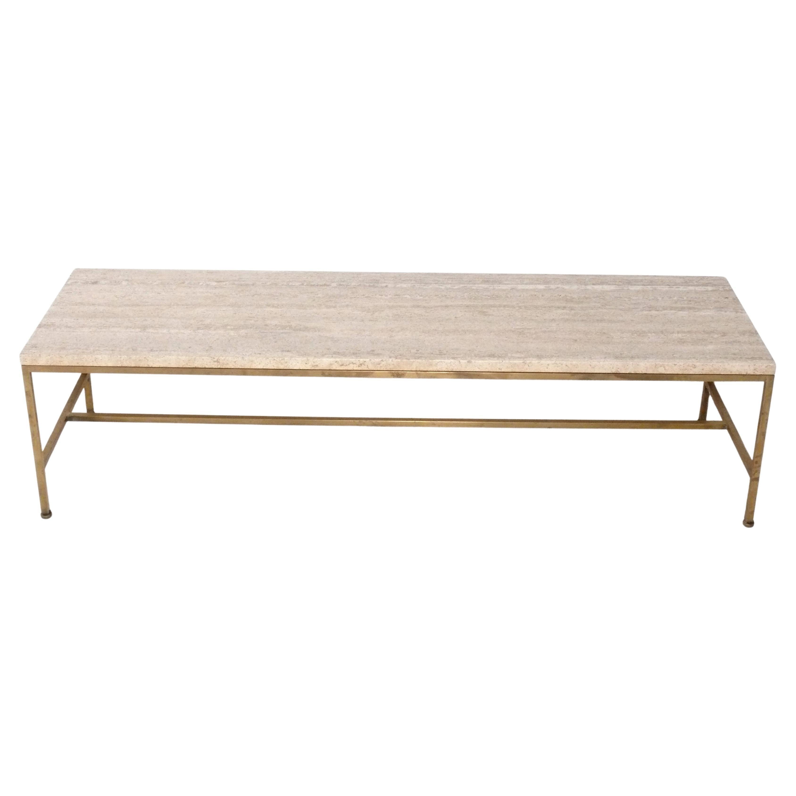 Elegante table basse en travertin et laiton, conçue par Paul McCobb, américain, vers les années 1950. Il présente un design architectural aux lignes épurées. Le laiton conserve sa patine d'origine avec diverses taches et usures dues à l'âge. Si vous
