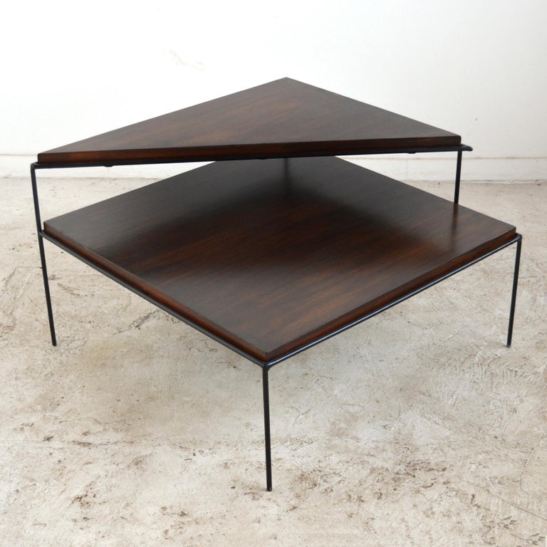 McCobb's graphic sensibility and command of line is most evident in his design with iron frames. Designs like this large two-tiered corner table with a triangular upper surface floating above a square table. Deceptively simple in execution, the