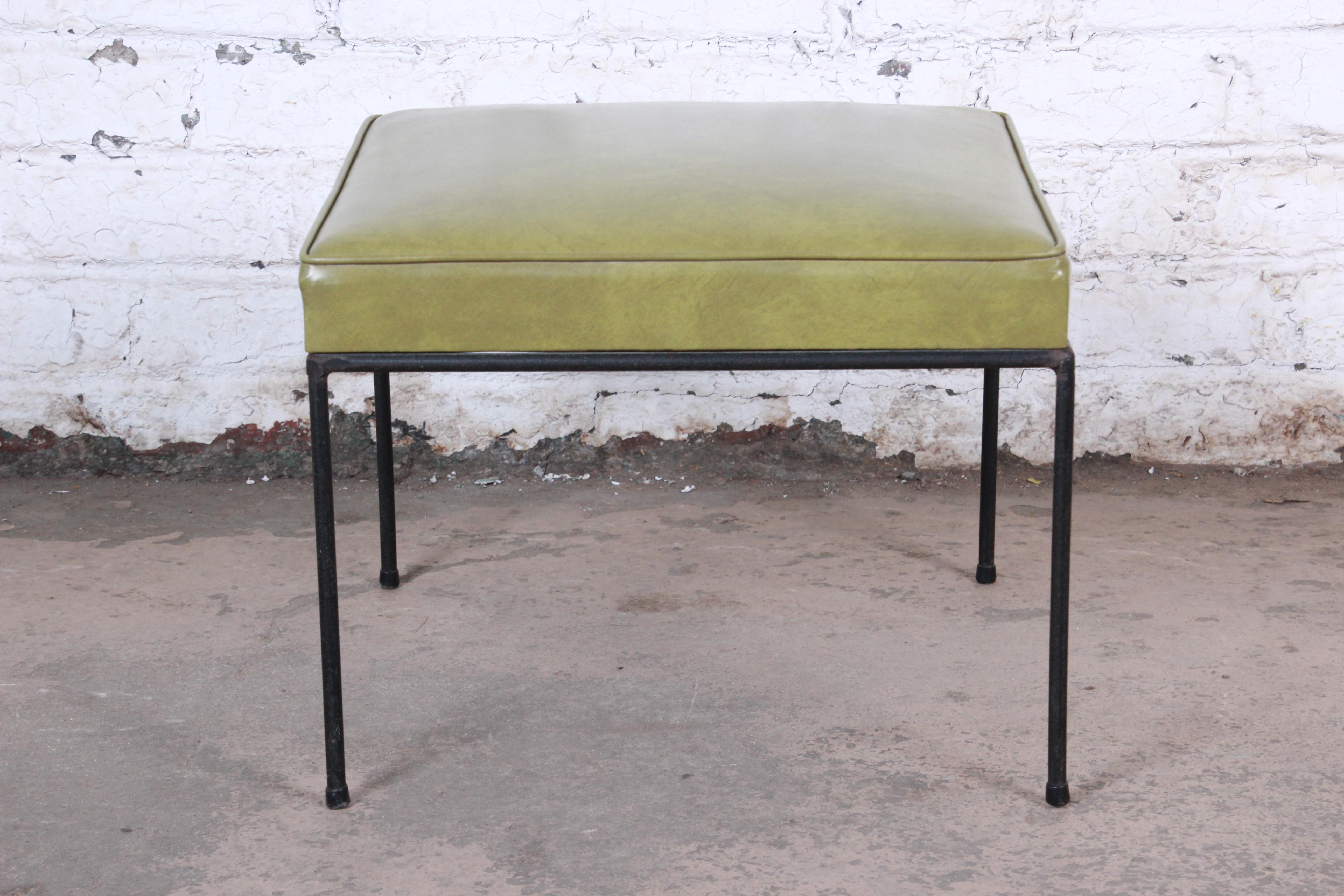 A stylish Mid-Century Modern stool or ottoman designed by Paul McCobb. The stool features nice black iron legs with all feet glides still intact. The green vinyl upholstery is original. An excellent example of McCobb's Minimalist design work. The