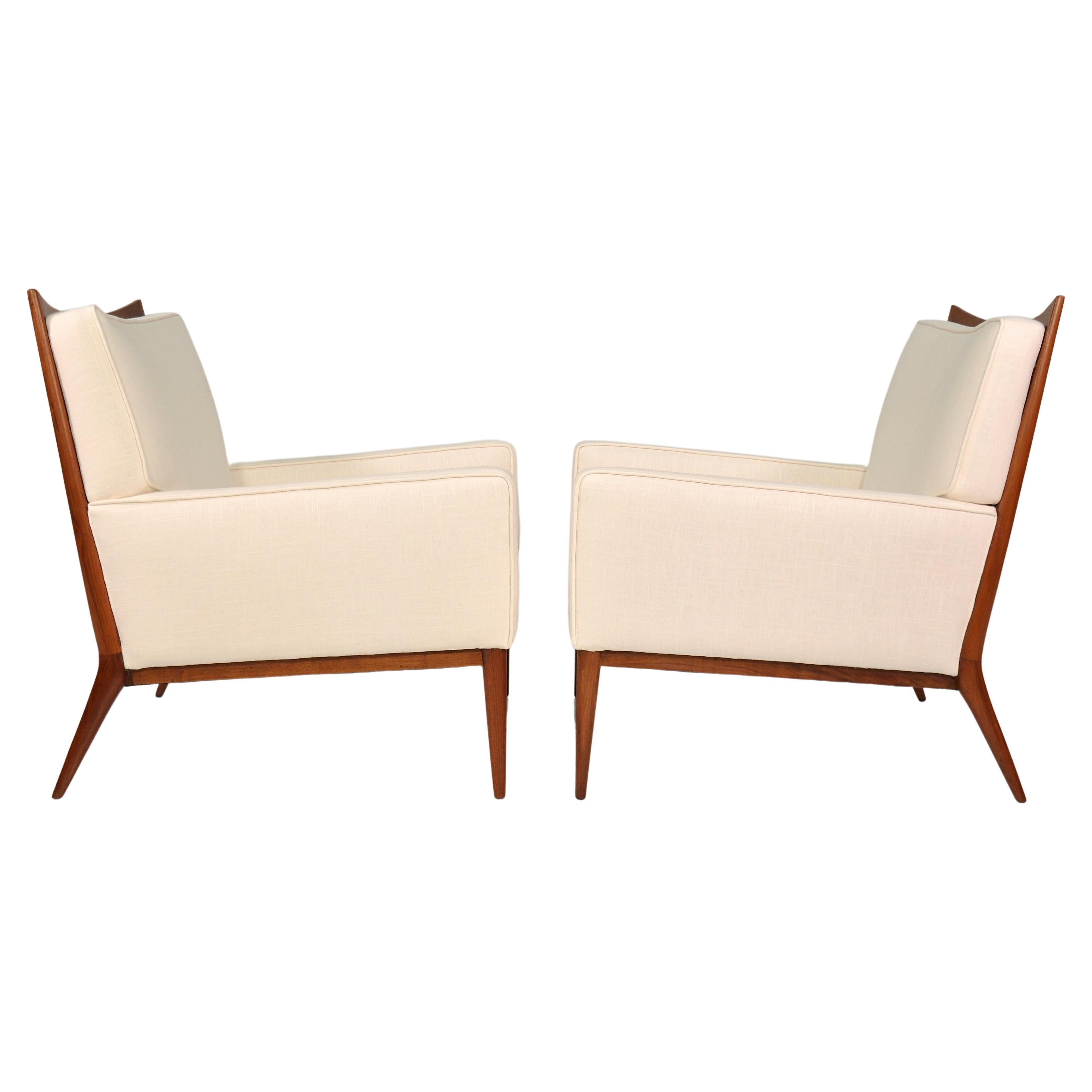 Exquisite pair of Paul McCobb Mid-Century Modern model 1322 armchairs from the coveted Directional collection, dating from the 1950s. The refinished chairs have been recovered in an off-white Belgian linen. The beautifully sculpted walnut frames