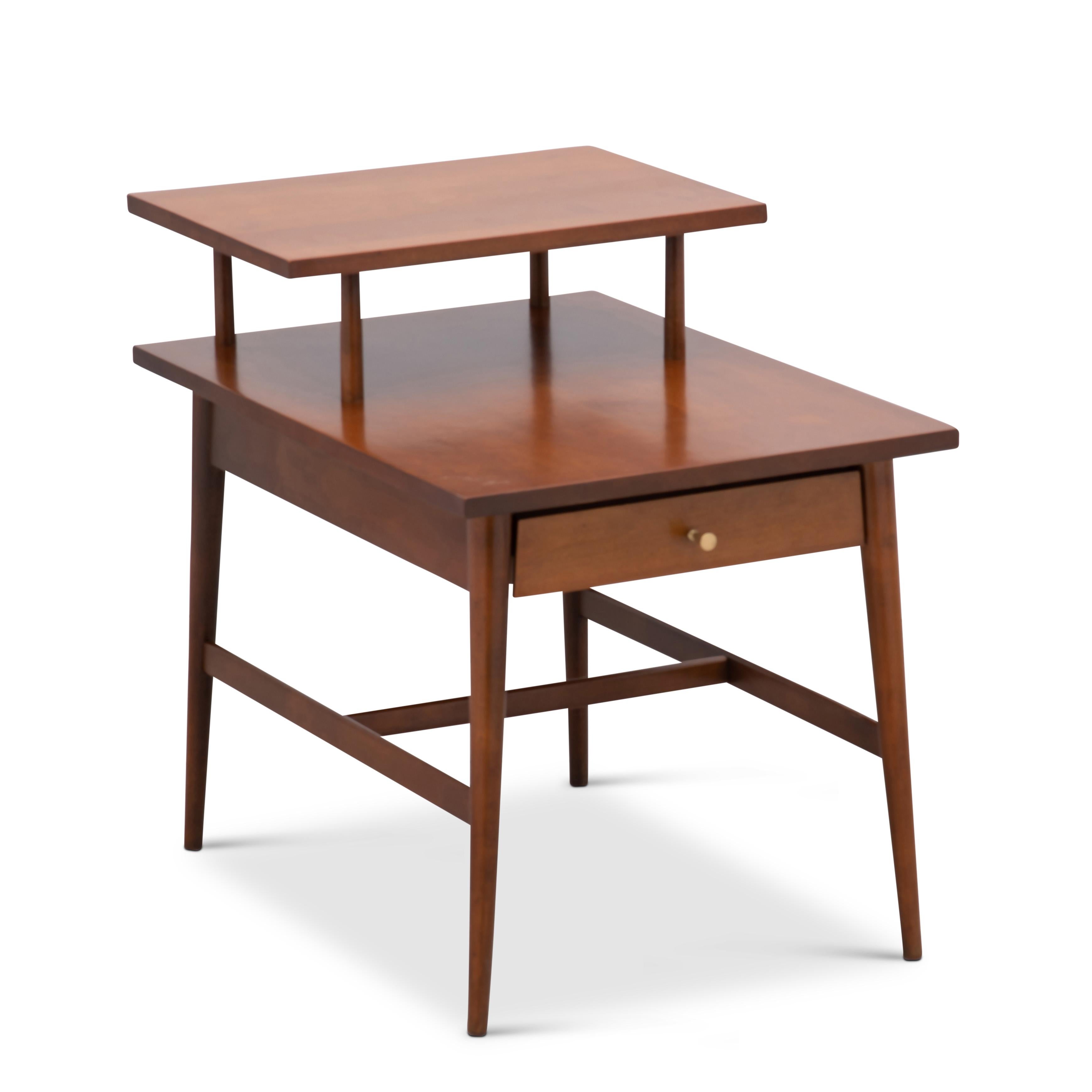 An early Paul McCobb #1589 step table for the Planner Group, Winchendon Furniture. 1950s. Solid maple with a single drawer and signature McCobb hourglass brass pull.