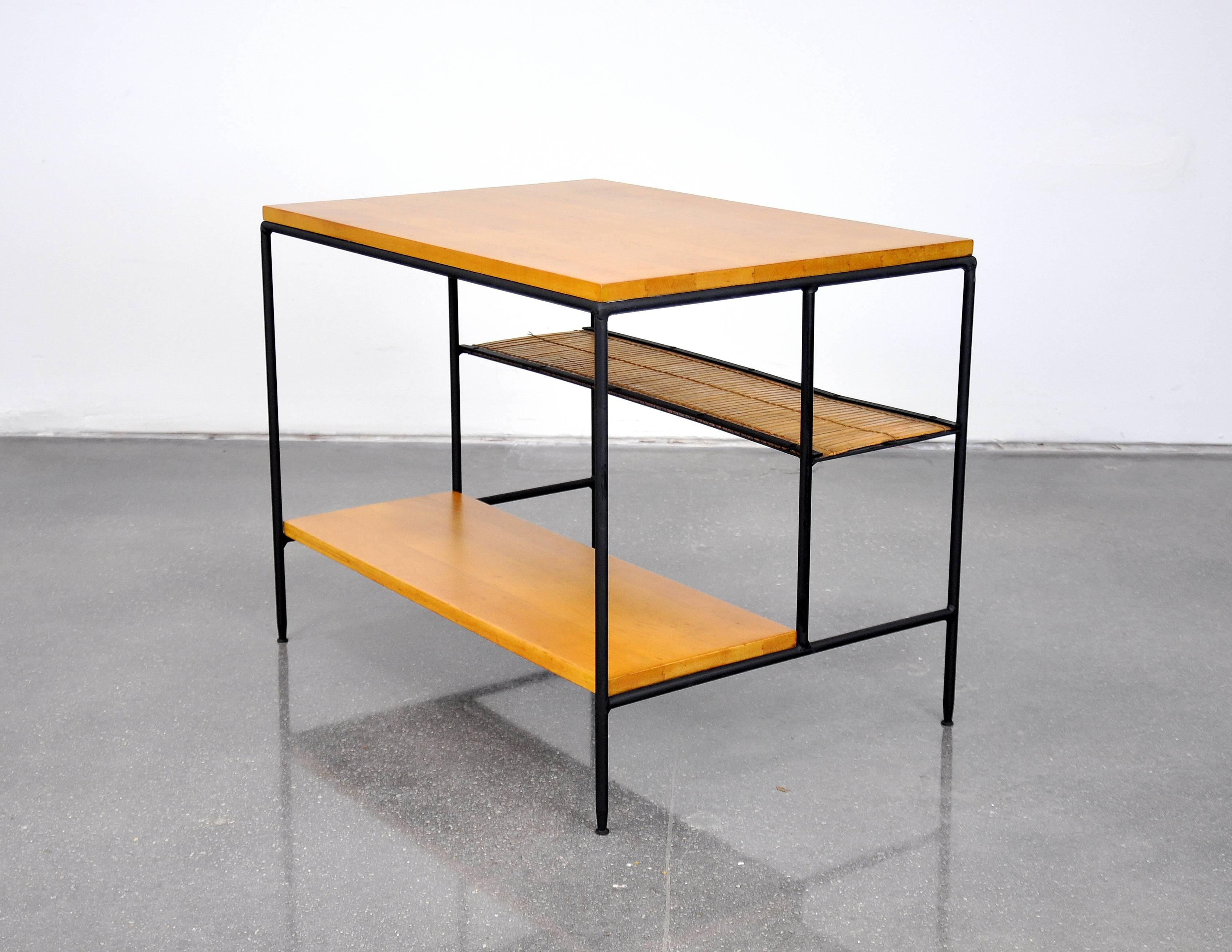 Vintage model 1578 Mid-Century Modern three-tiered end or occasional table designed by McCobb in the 1950s. The graceful black iron base is complemented by a two-tiered lower section with one solid and one bamboo slatted shelf. The simplicity of the
