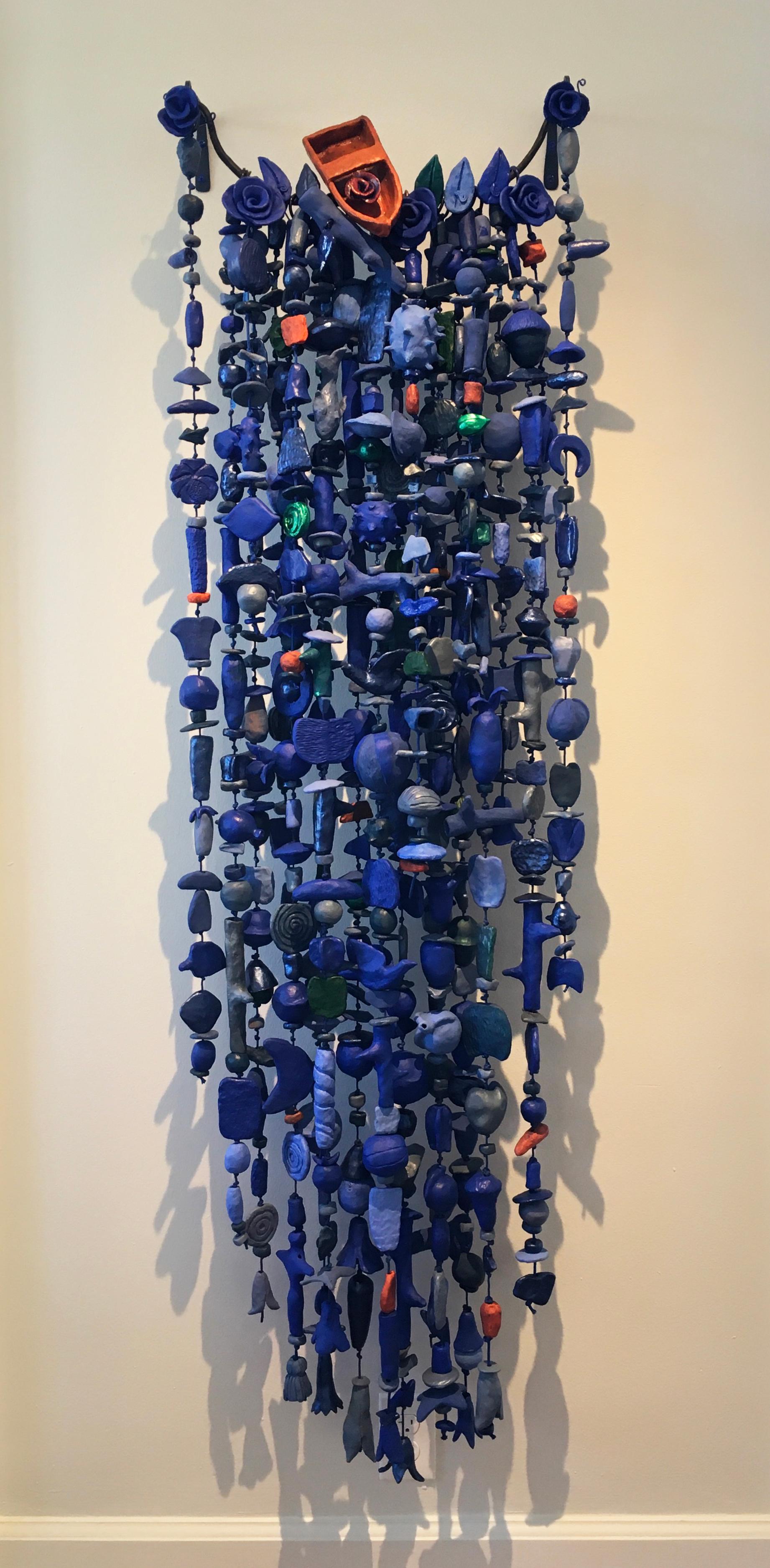 'Waterfall,' by Paul Medina is a ceramic and mixed media suspended sculpture, measuring 60 x 28 x 9 inches, and comprises strands of low-fired clay elements, connected by nylon cord hanging from a steel rod and brackets.
The majority of clay forms