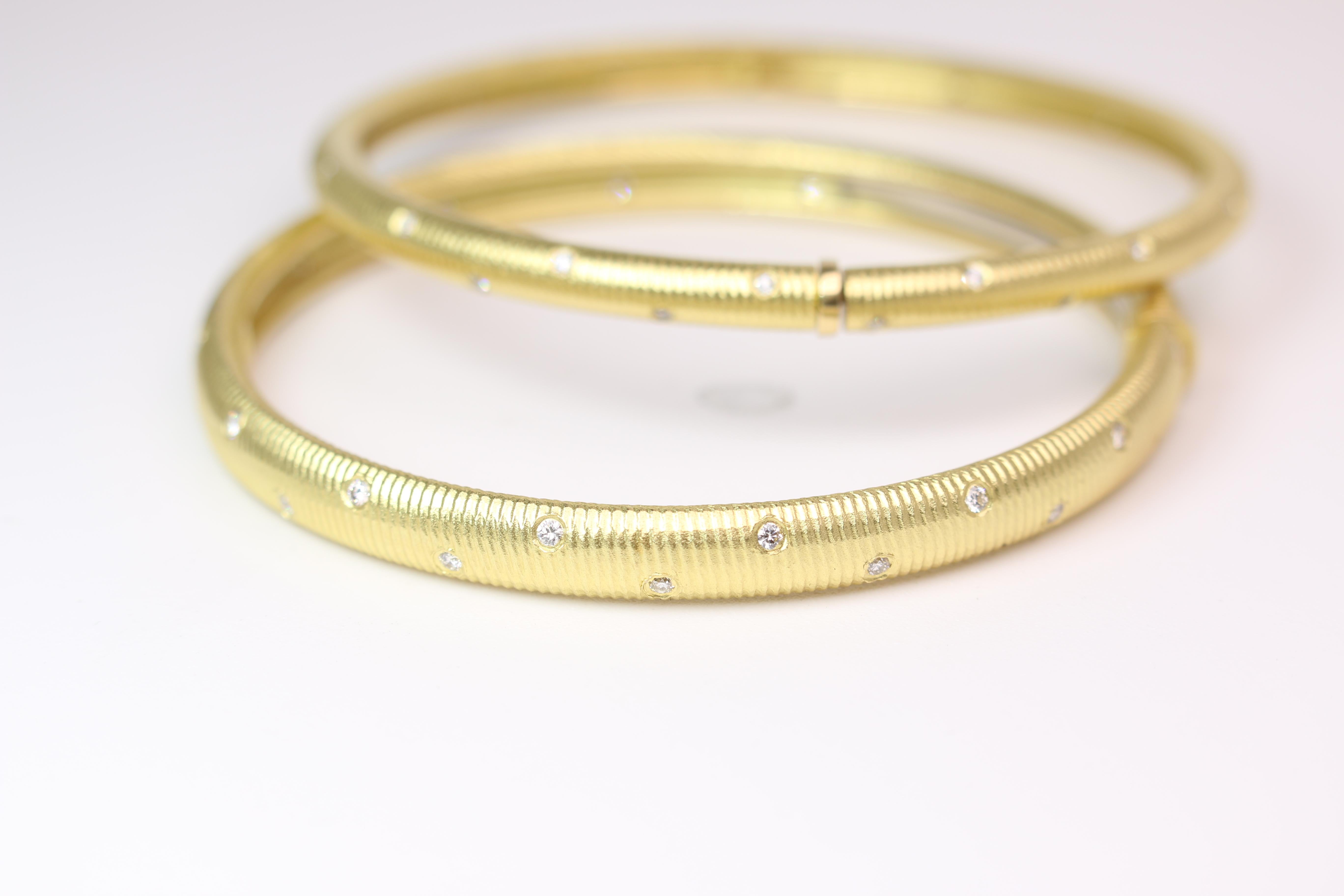 Paul Morelli bangle set in 18K yellow gold .The bangles have a ribbed finish and are accented with brilliant round cut diamonds. An expandable mechanism allows for the bangles to comfortably slide on and off. One bangle has an approximate width of