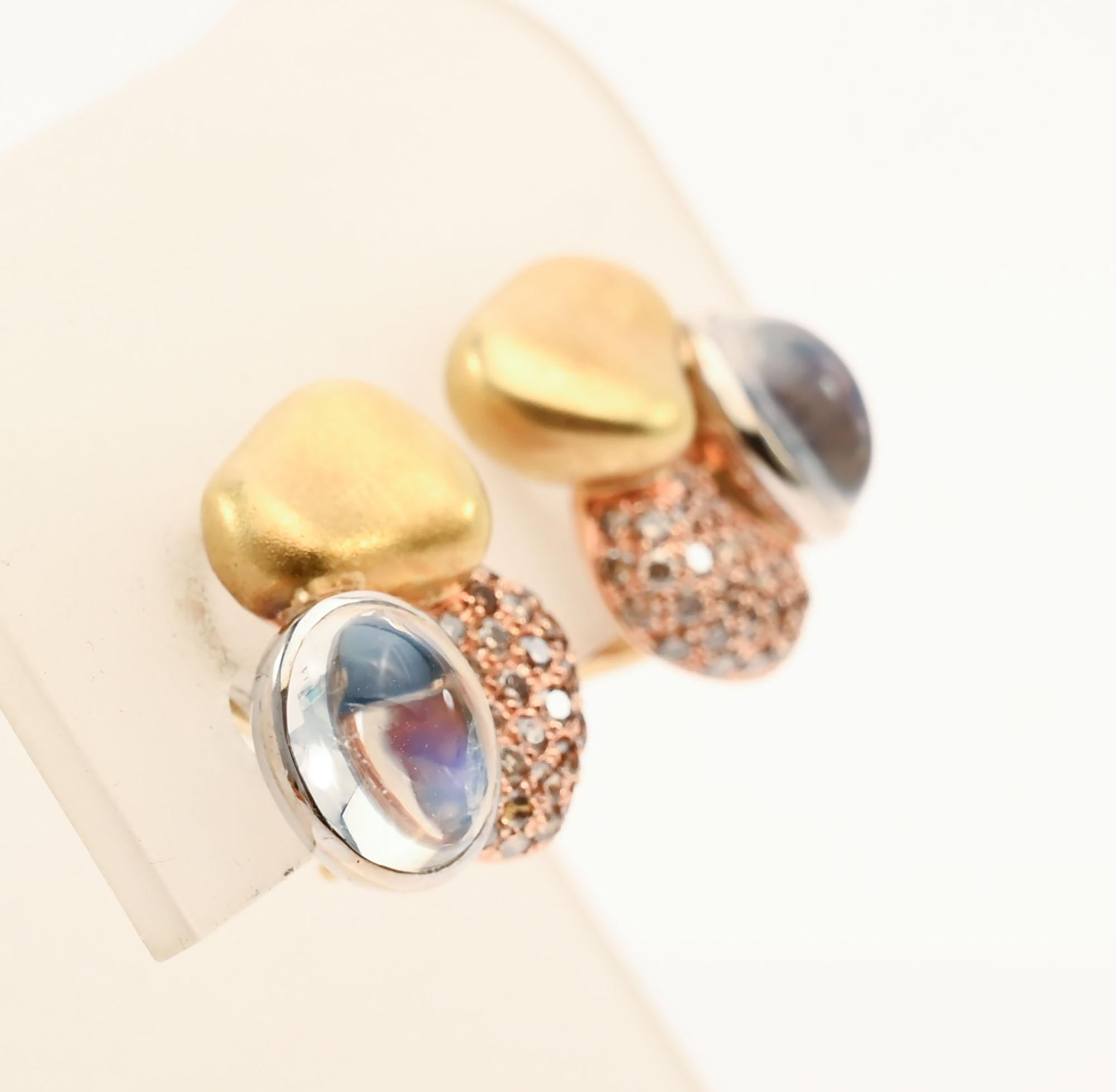 Insoliti orecchini di Paul Morelli, piccoli nelle dimensioni ma grandi nel design. Tre elementi di forme e materiali diversi vengono combinati per creare una forma scultorea. Una pietra di luna ovale cabochon è sormontata da una forma d'oro