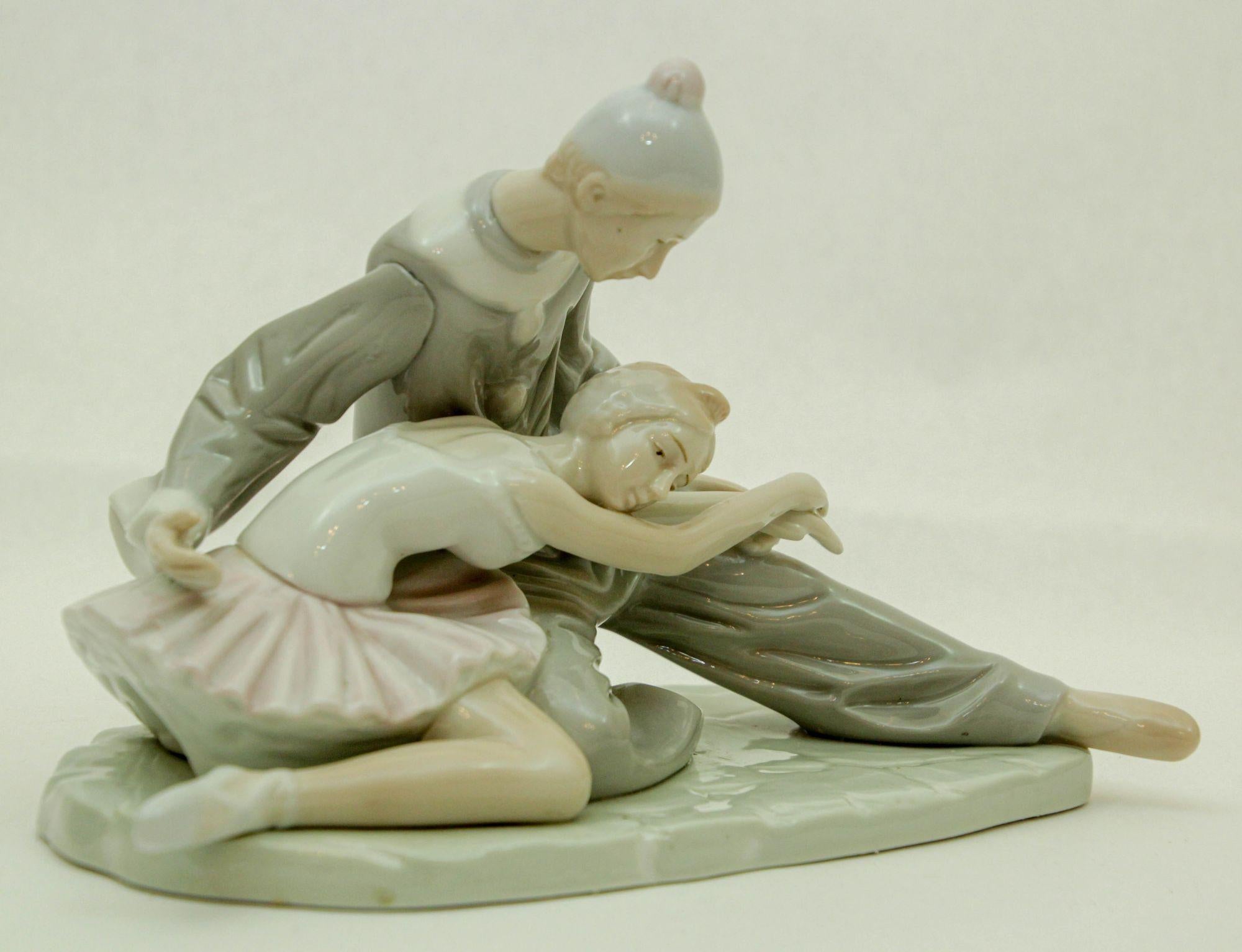 Beautifully sculpted Porcelain Ballet Dancer and Ballerina sitting on the Floor. The ballerina is resting her head on the lap of her make partner.
Gray and white ceramic figurine featuring a stunning Ballerina Dancer and Jester Clown in a detailed