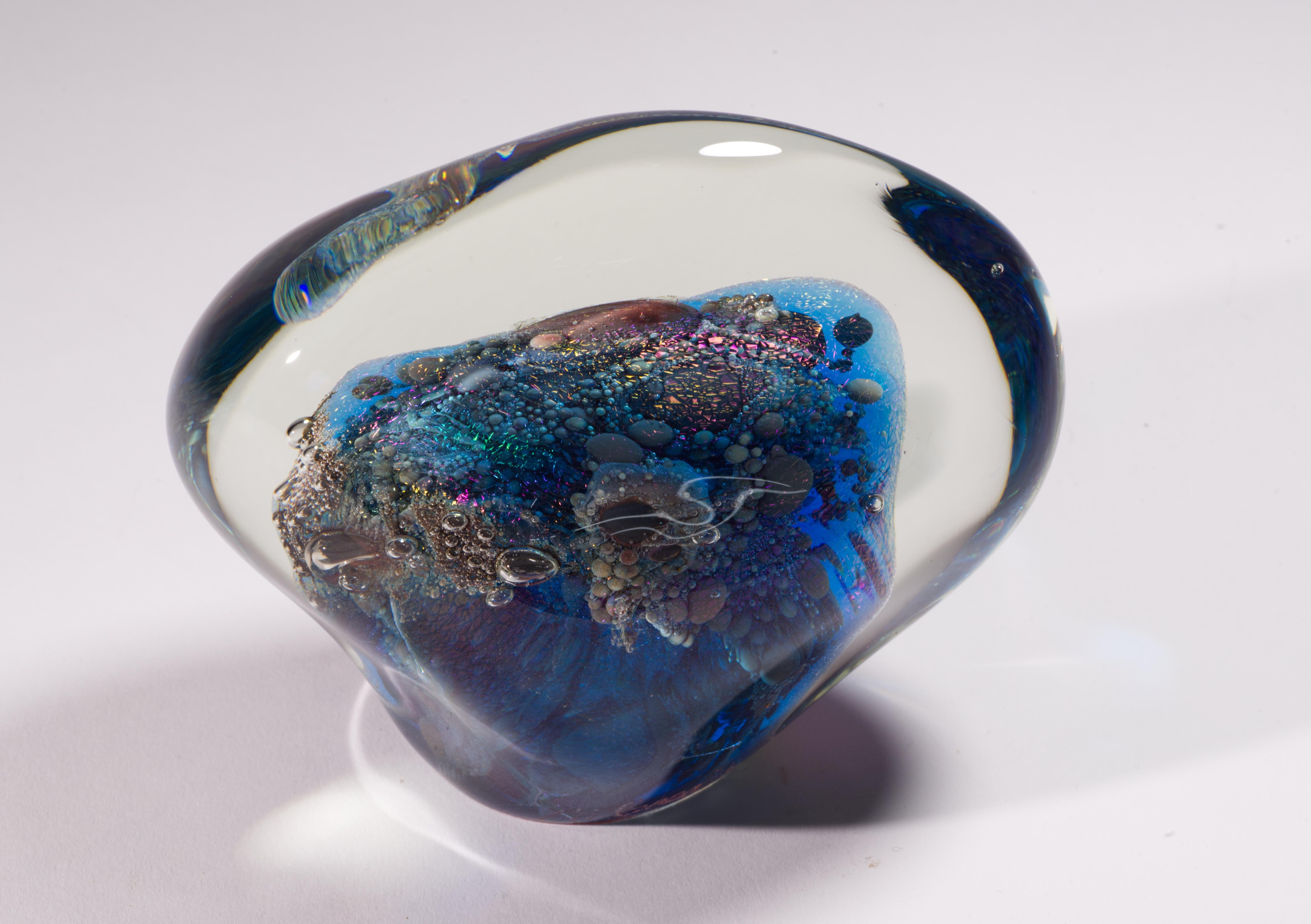  Cette sculpture en verre d'art ou presse-papier complexe et saisissante présente un noyau central fusionné avec des bulles contrôlées, des pigments multicouches et du verre dichroïque qui est enveloppé dans une couche de verre transparent selon la