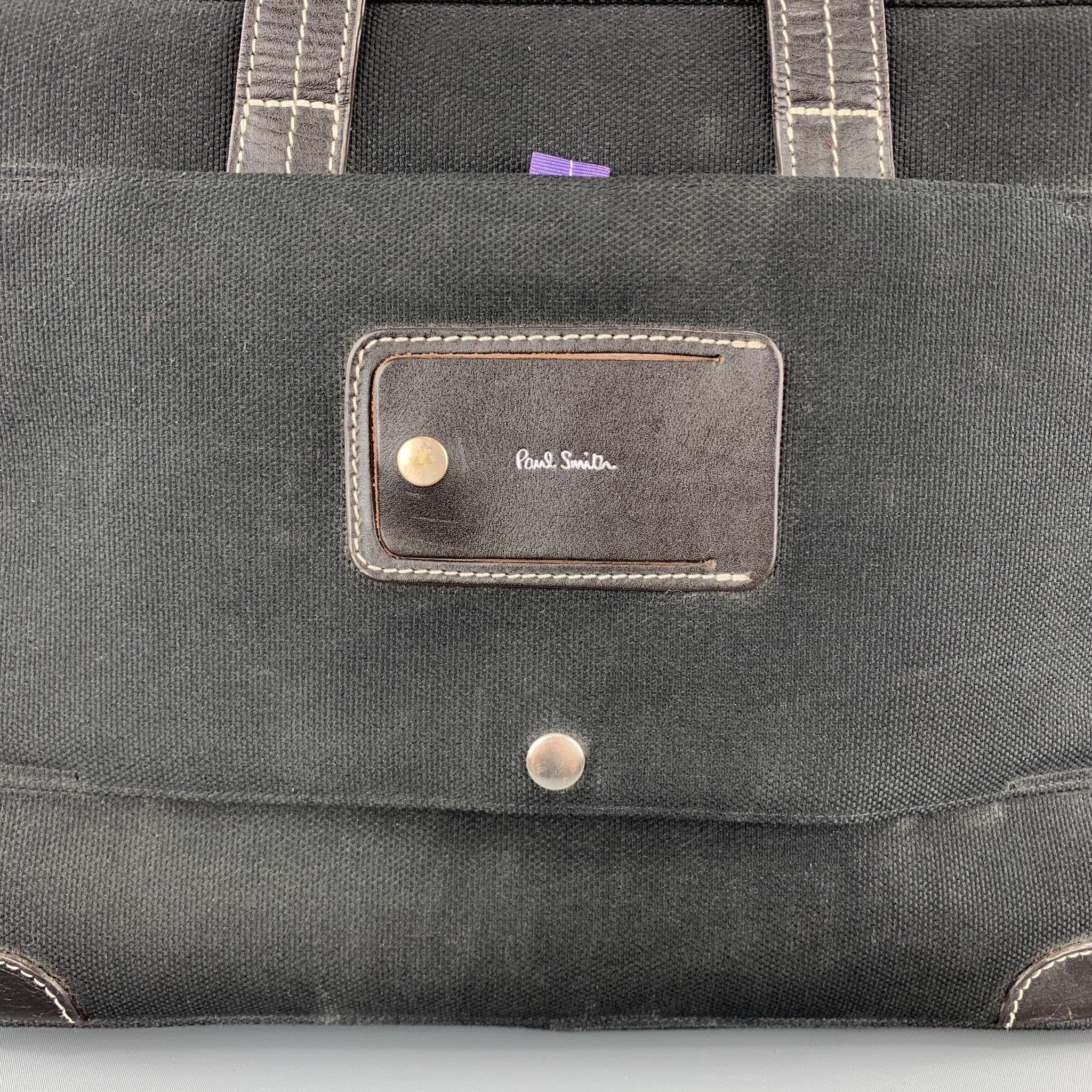 PAL SMITH work bag comes in black canvas with black leather trim, contrast stitching, double top handles, detachable strap, and purple multi-compartment interior.
Good
Pre-Owned Condition. 

Measurements: 
  Length: 15.5 inches Width: 6 inches