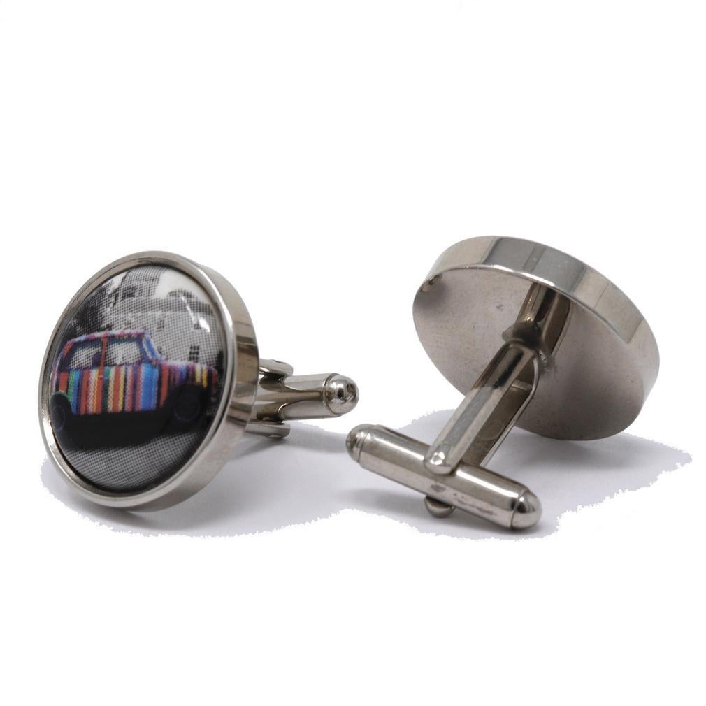 Paul Smith London Taxi Cufflinks. Round silver tone metal frames with faces containing opposing enamel buttons depicting an enamel pixeated photo of a multi-colored Paul Smith striped London taxi parked in front of a brick building. Flat backs with