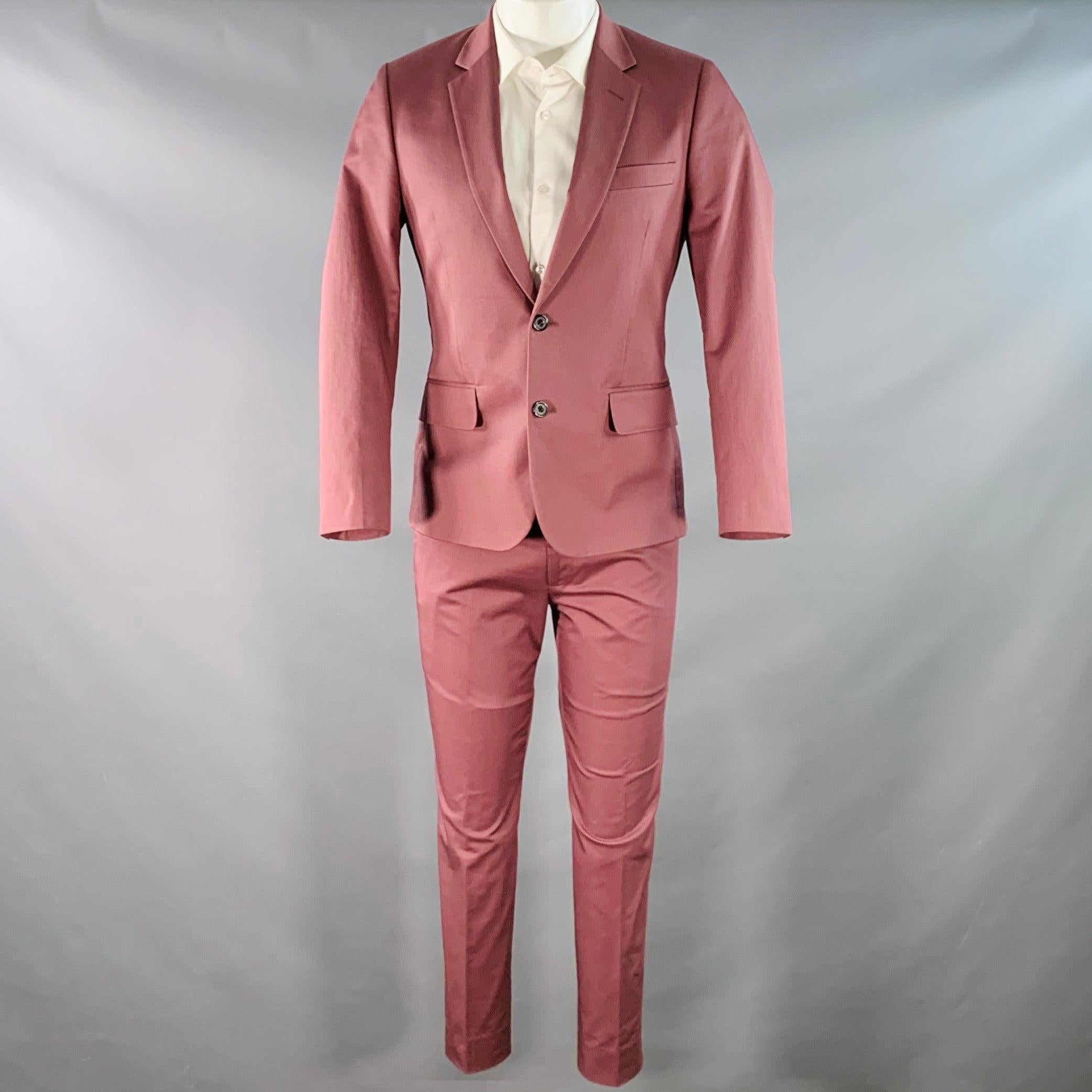 Costume de PAUL SMITH
dans un mélange de coton extensible bordeaux et mauve avec une doublure complète et comprend un manteau de sport à un seul boutonnage avec un revers à cran et un pantalon assorti à devant plat. Note : ce vêtement a été