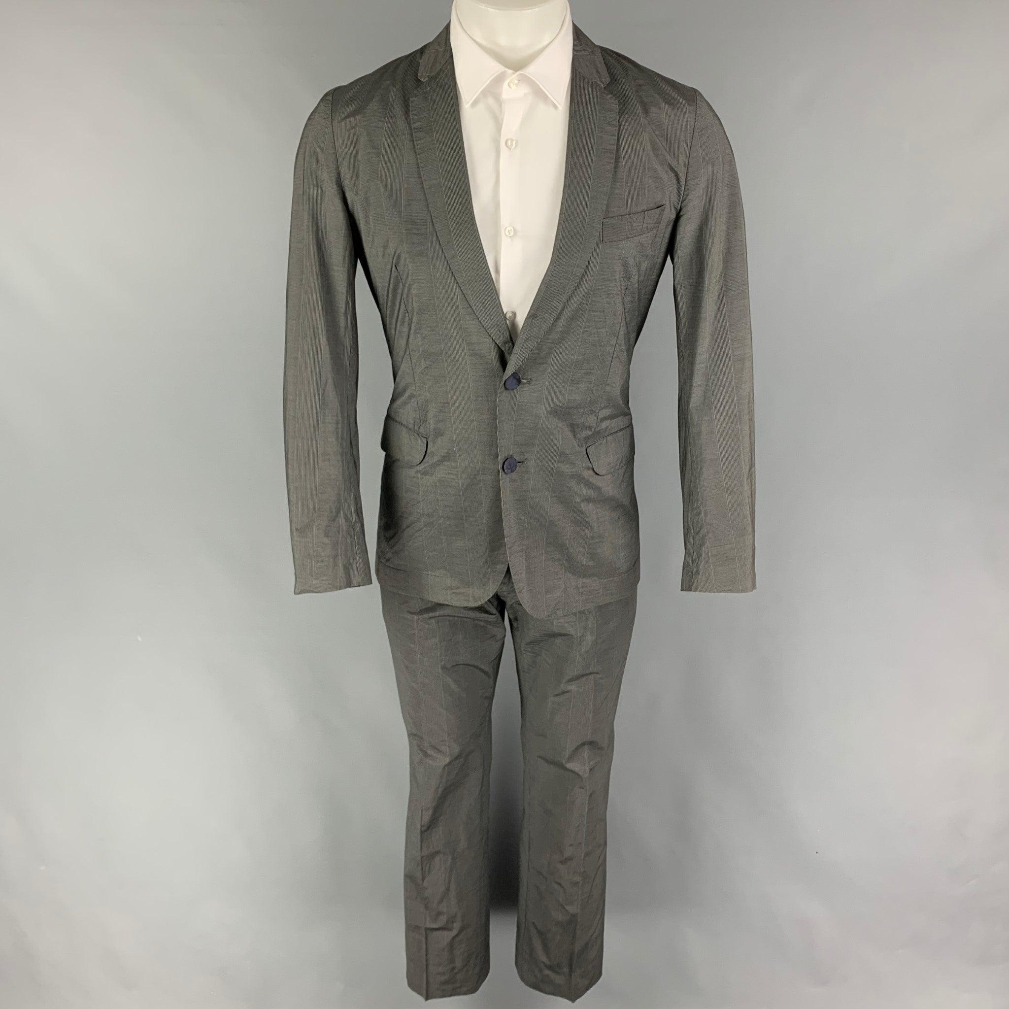 PAUL SMITH
suit comes in a gray glenplaid cotton / silk and includes a single breasted, double button sport coat with a notch lapel and matching flat front trousers. Good Pre-Owned Condition.
Light marks at front. Missing pants button closure. 